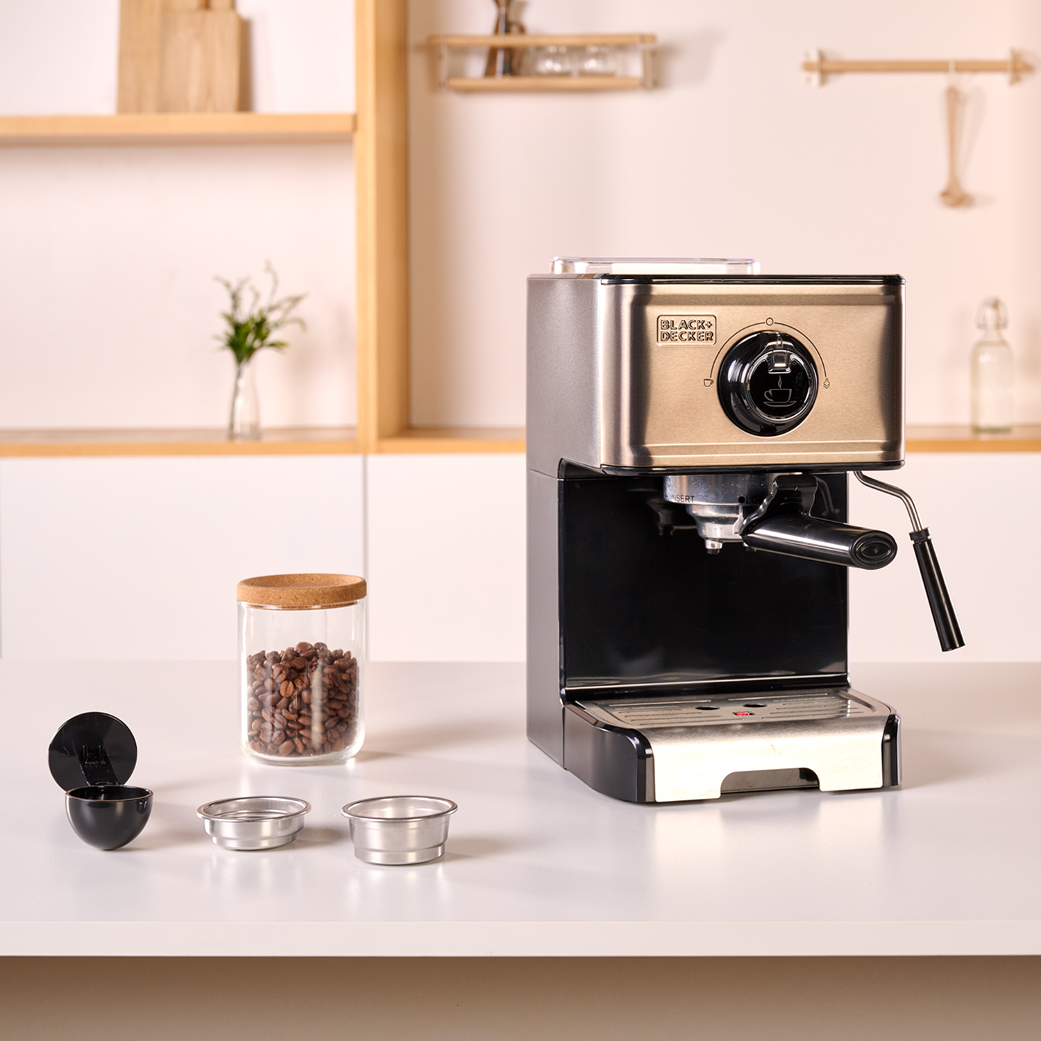Ekspres do kawy z akcesoriami na białej powierzchni. Obecny jest również szklany słoik z ziarnami kawy.