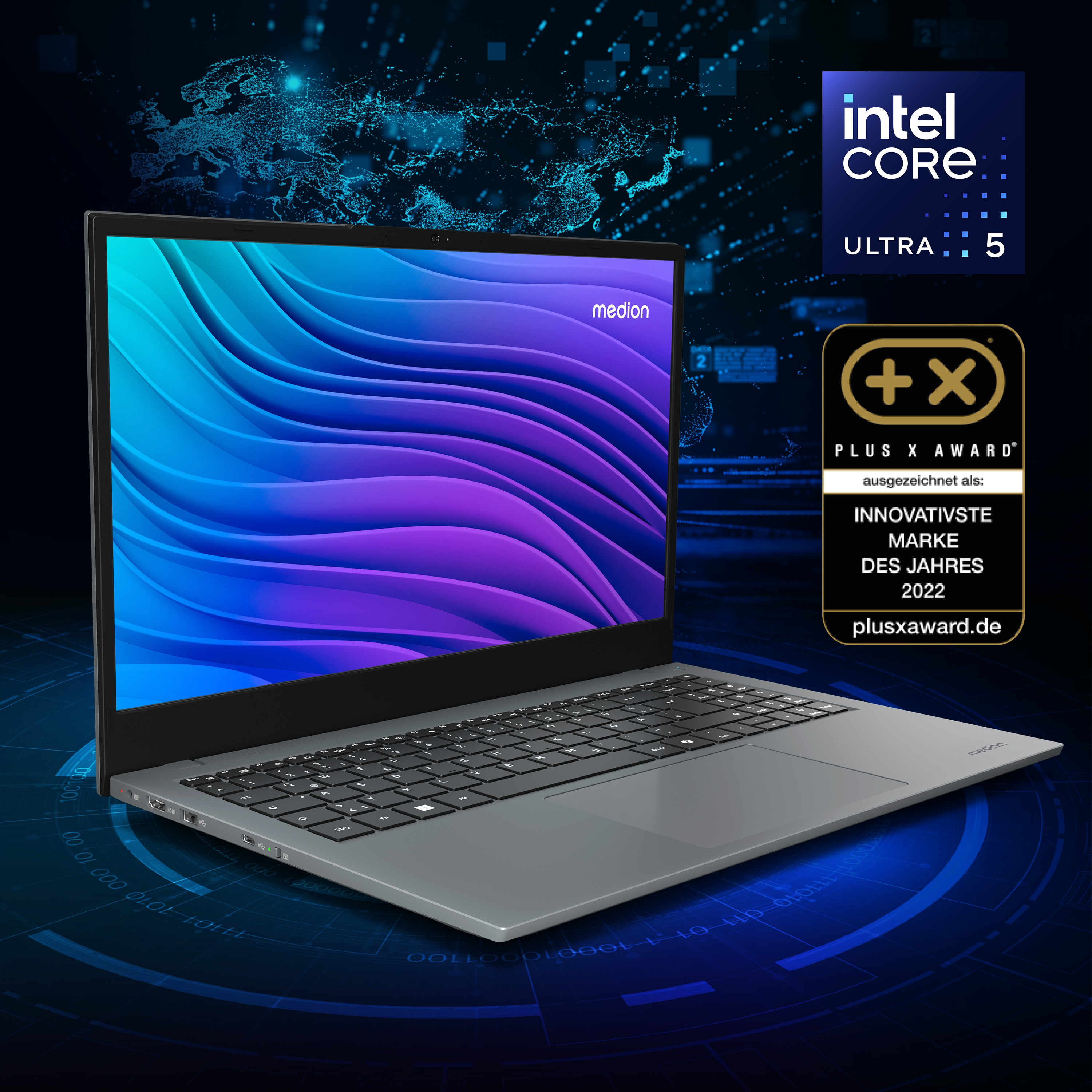 Laptop z niebiesko-fioletowym gradientem na ekranie. Widoczna odznaka Intel Core Ultra 5 i nagroda Plus X Award.