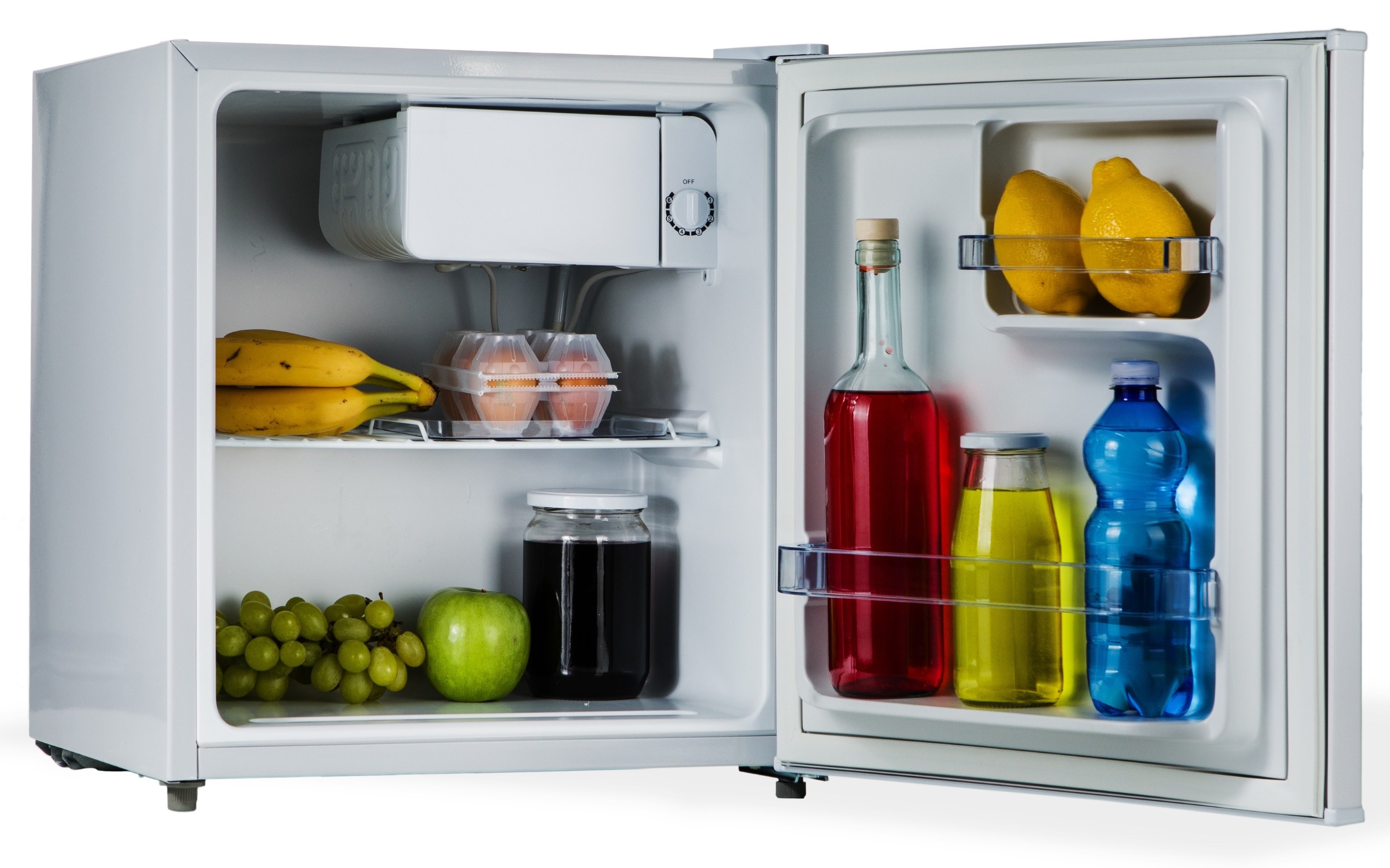 Interno del frigorifero, porta aperta. Ha frutta, bevande e cibo. Ripiano con banane e altro cibo.
