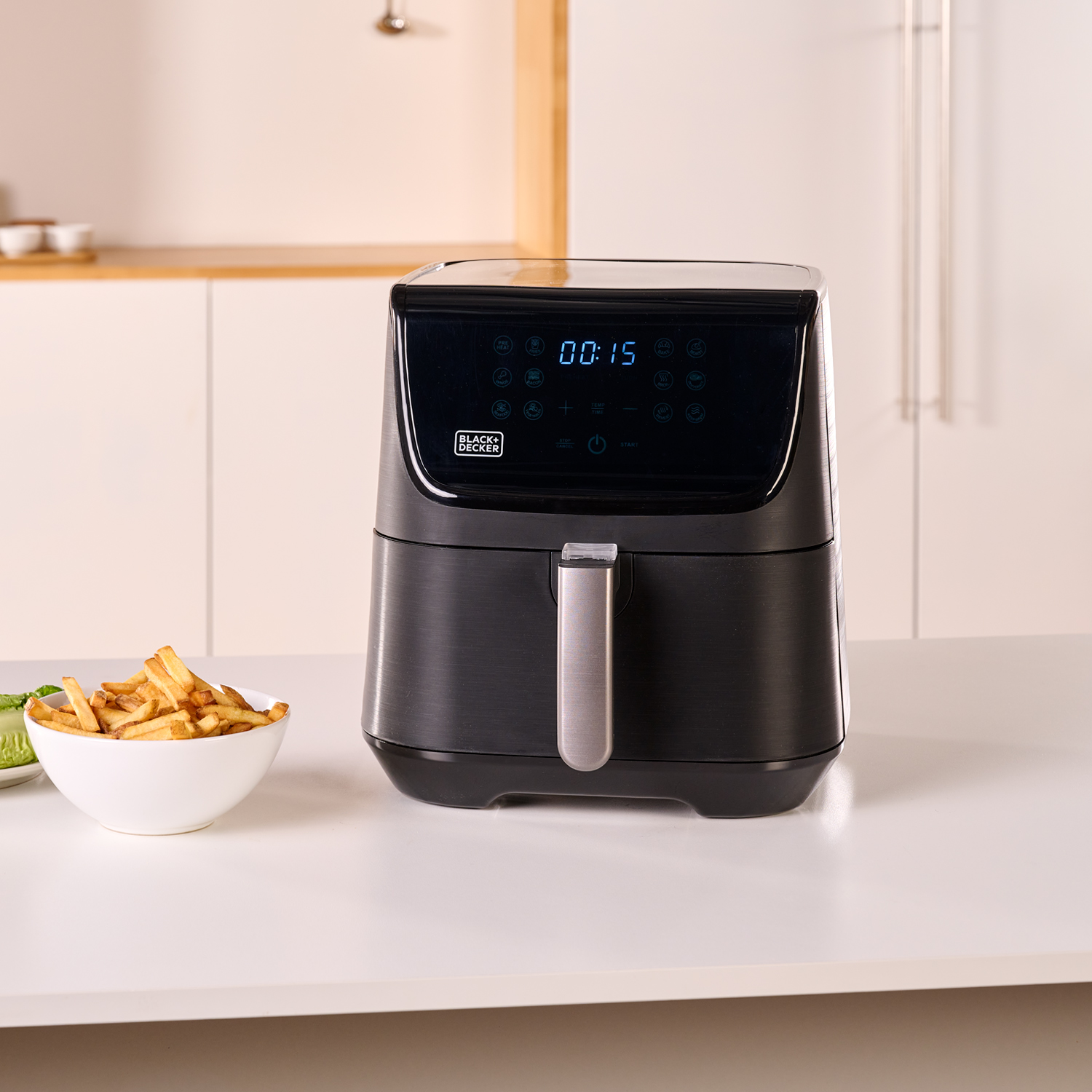 Czarna frytkownica z wyświetlaczem, biała miska frytek na stole.