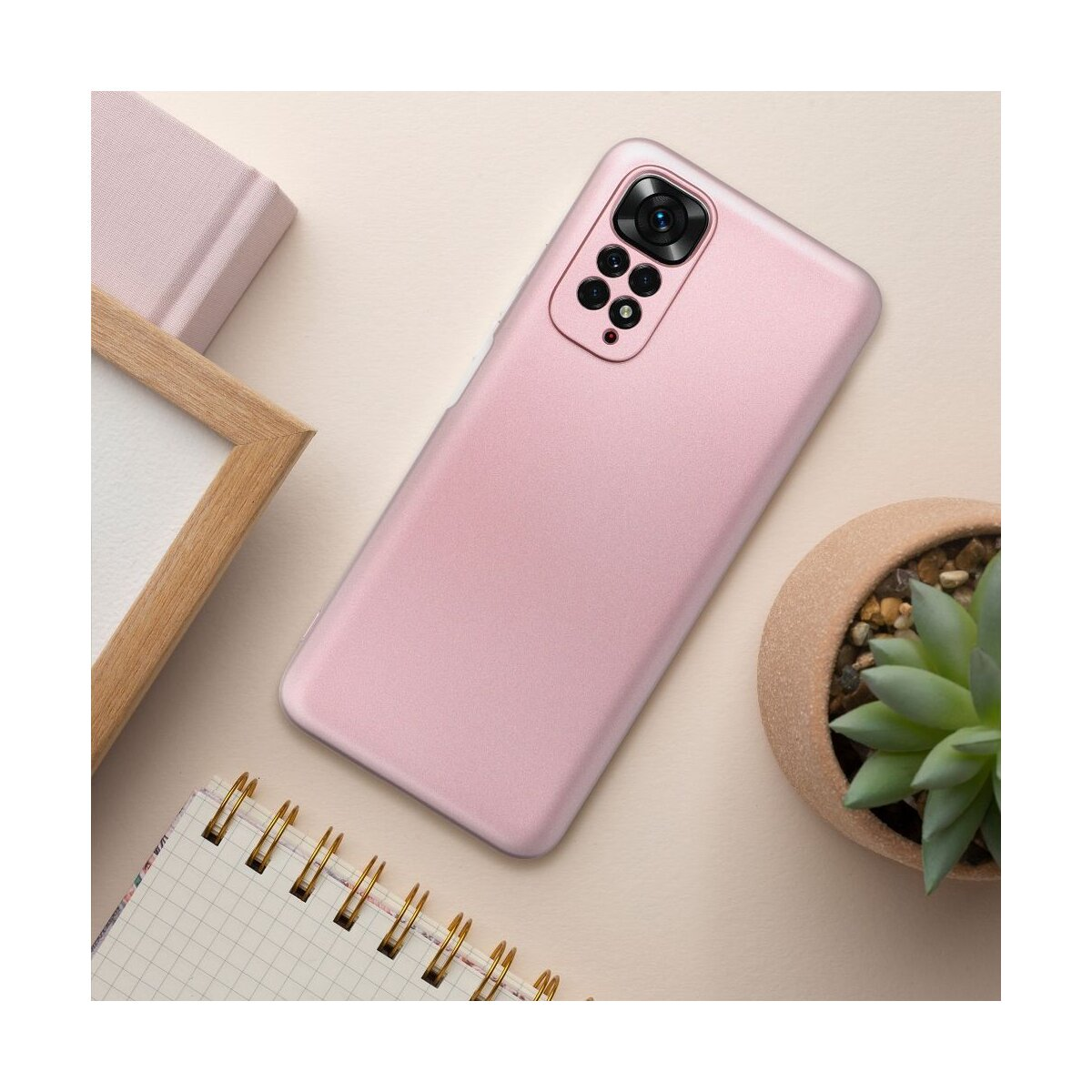 Telefono rosa con custodia su un tavolo, con quaderno e pianta.