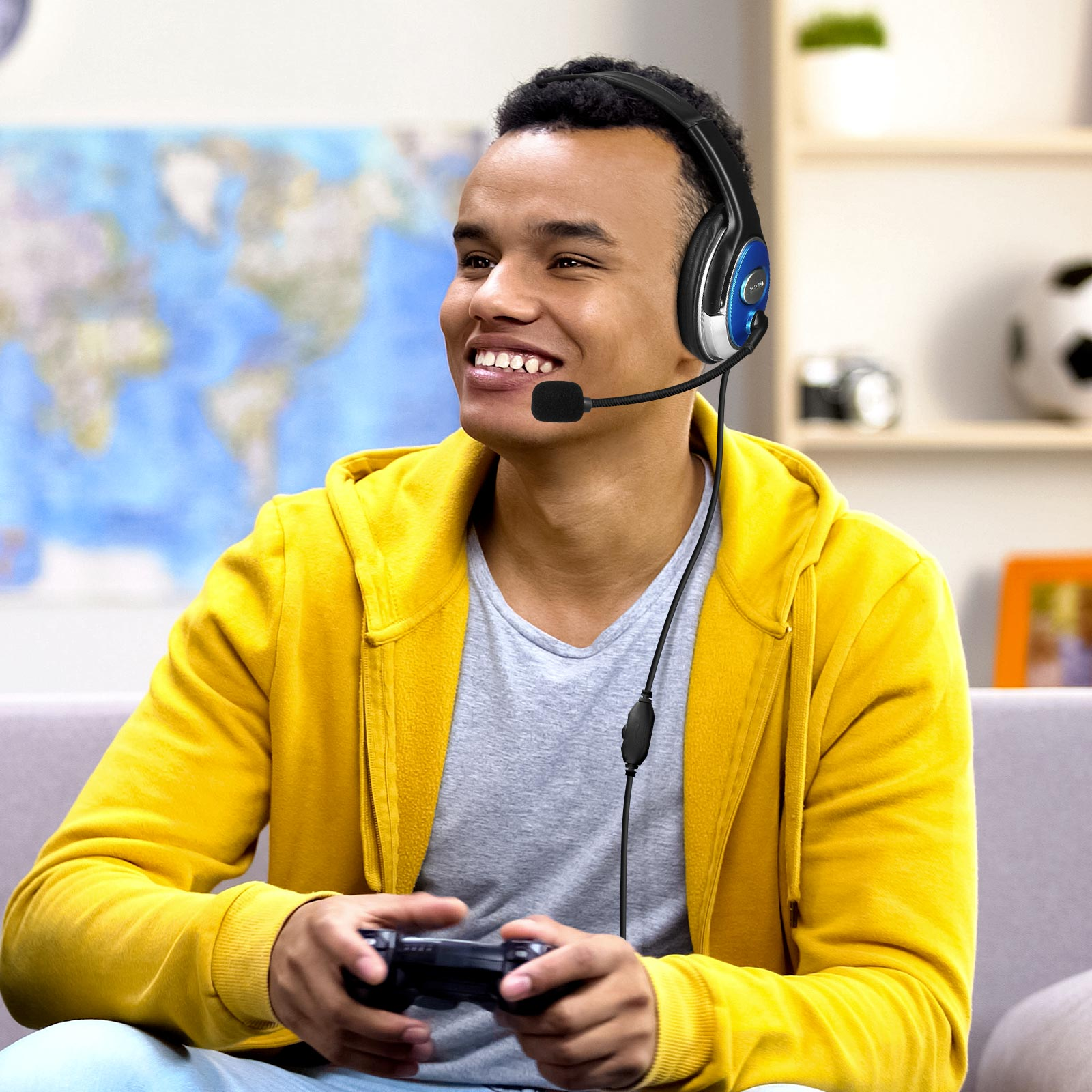 Un jeune homme sourit en portant un casque de jeu et en tenant une manette.