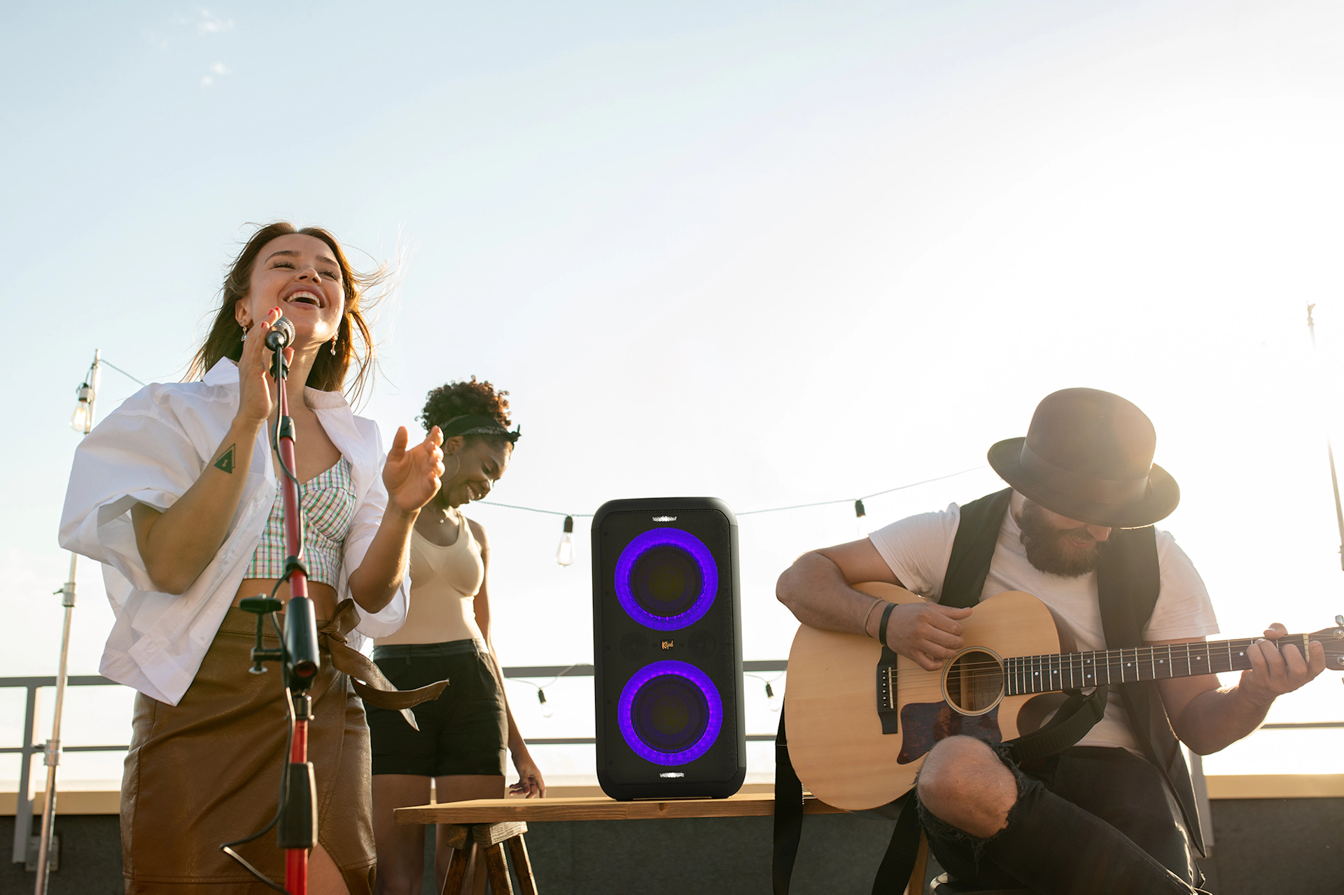 Gruppo di persone che si esibiscono su un tetto, con altoparlante e chitarra.