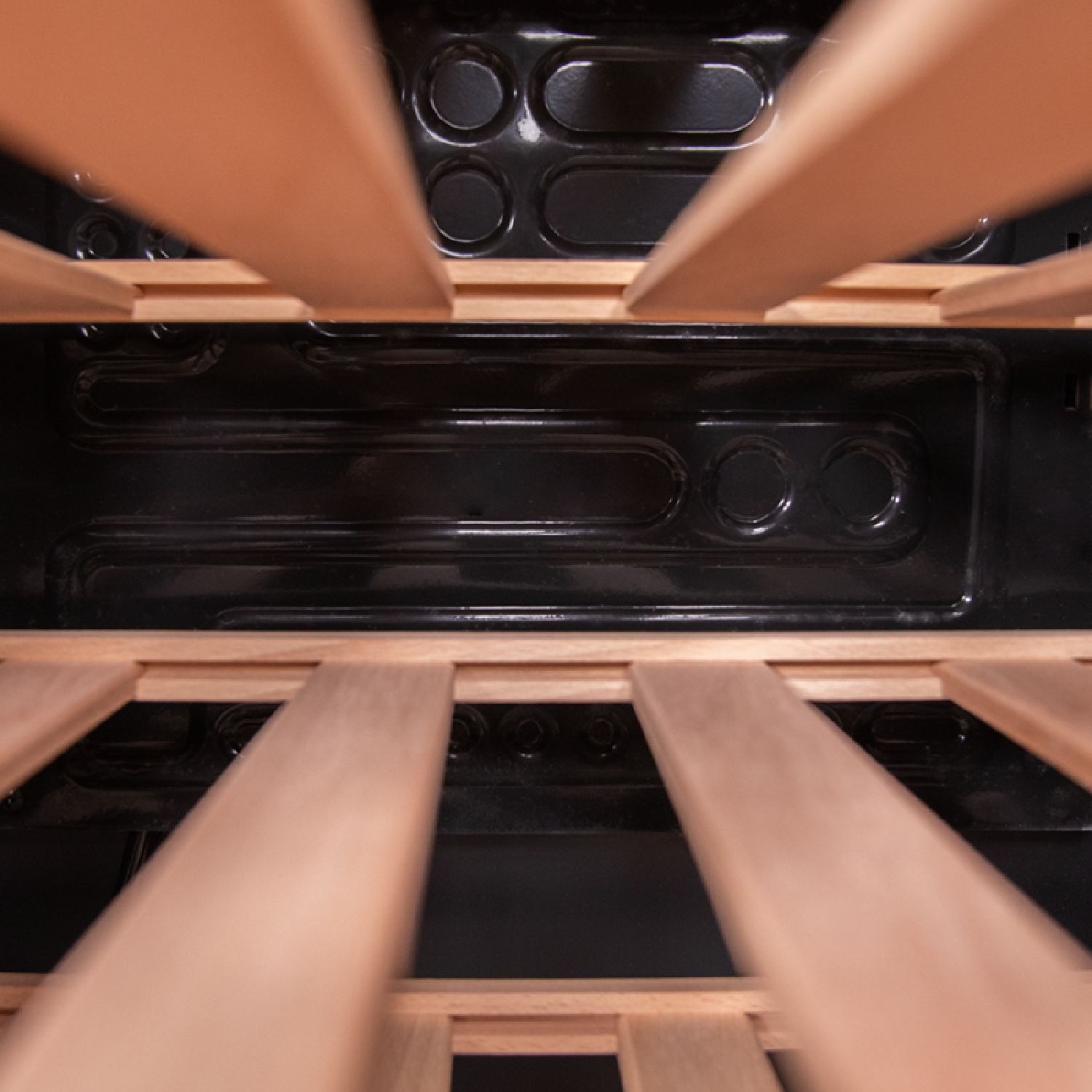 Innenraum eines Weinregals aus Holz mit mehreren Regalen, dunklem Innenraum und einigen sichtbaren Weinflaschen.
