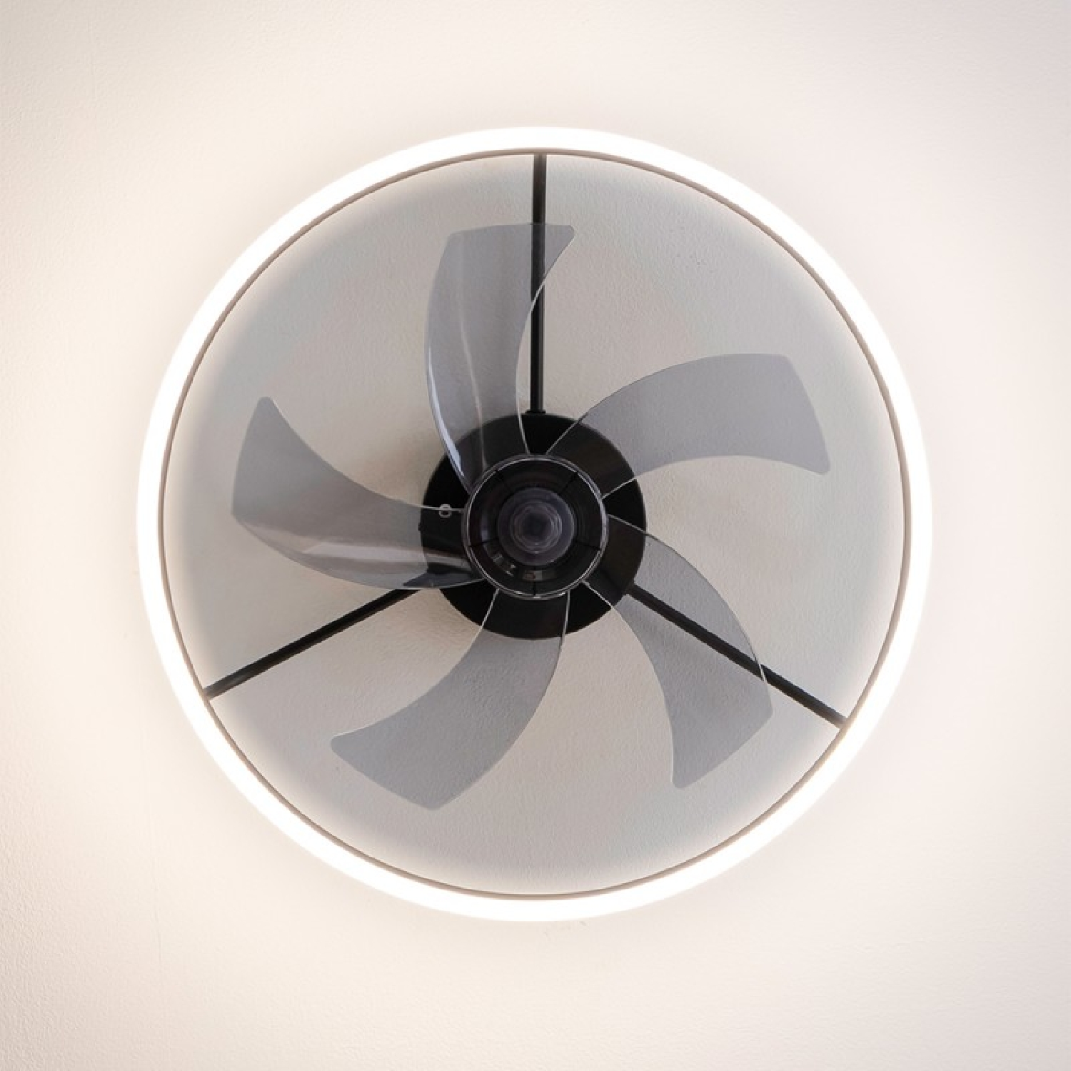Deckenventilator mit fünf grauen Flügeln und einem kreisförmigen Licht an einer weißen Decke.