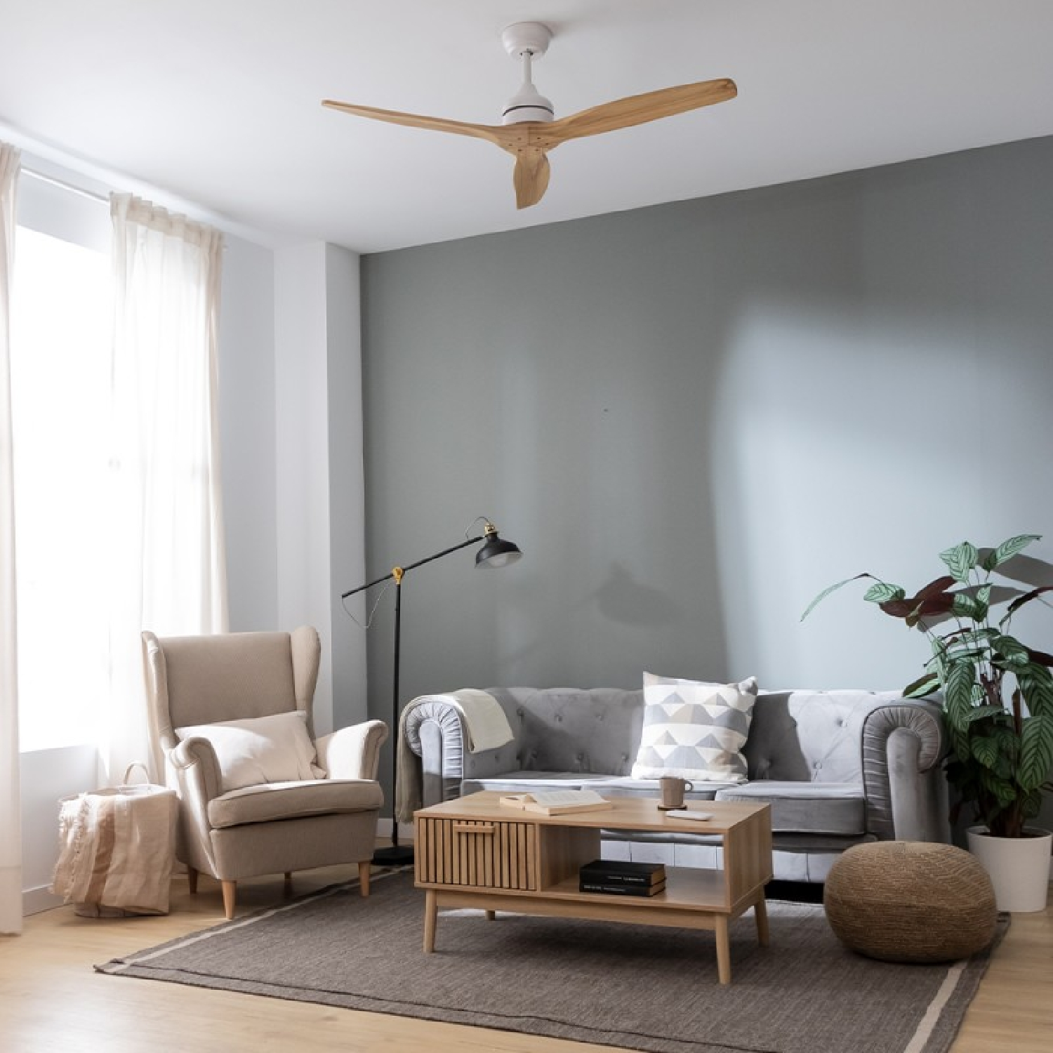 Wohnzimmer mit Ventilator. Der Ventilator hat drei Holzblätter, einen weißen Motor und ist an der Decke.