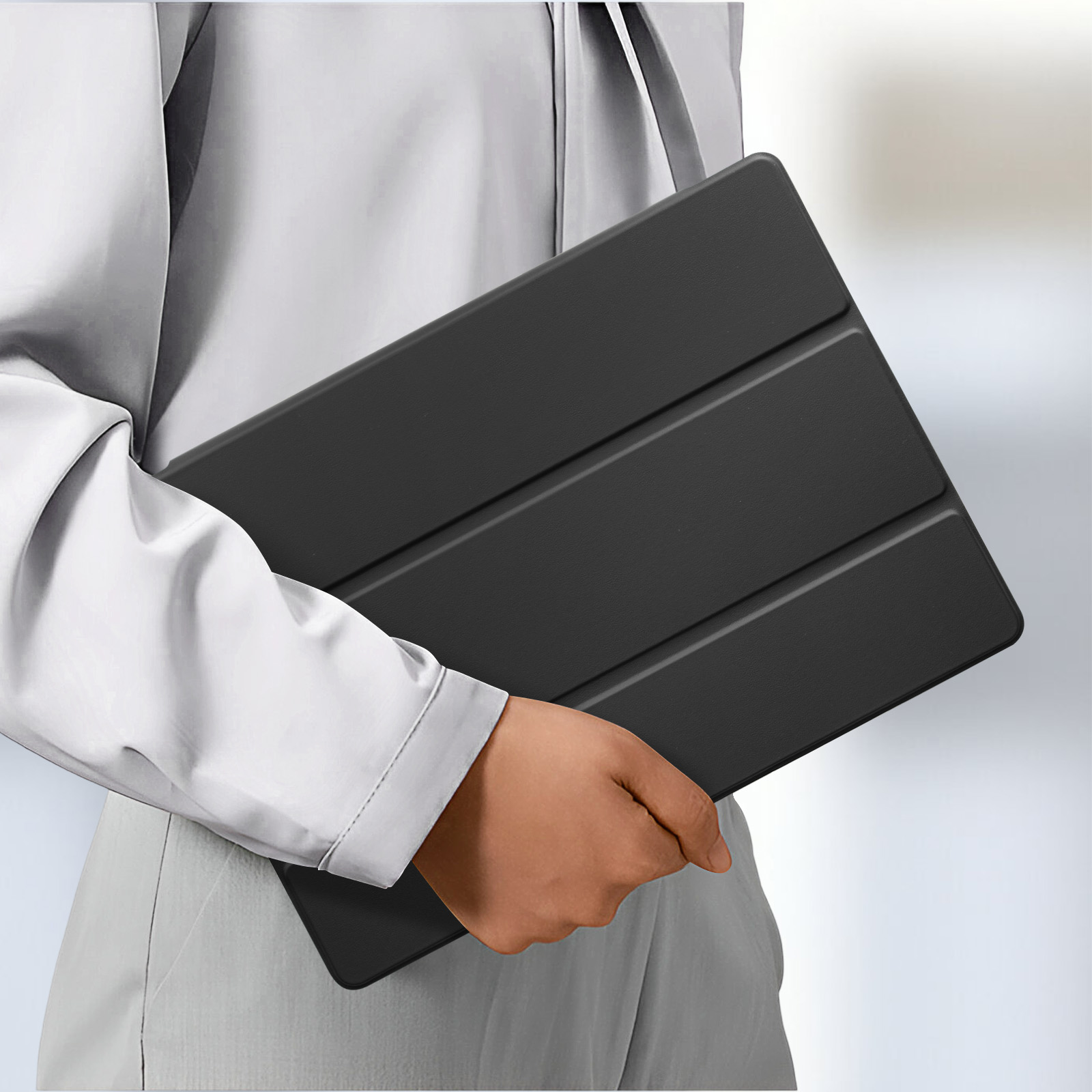 Persona che tiene una custodia per tablet nera chiusa, tre pieghe visibili.