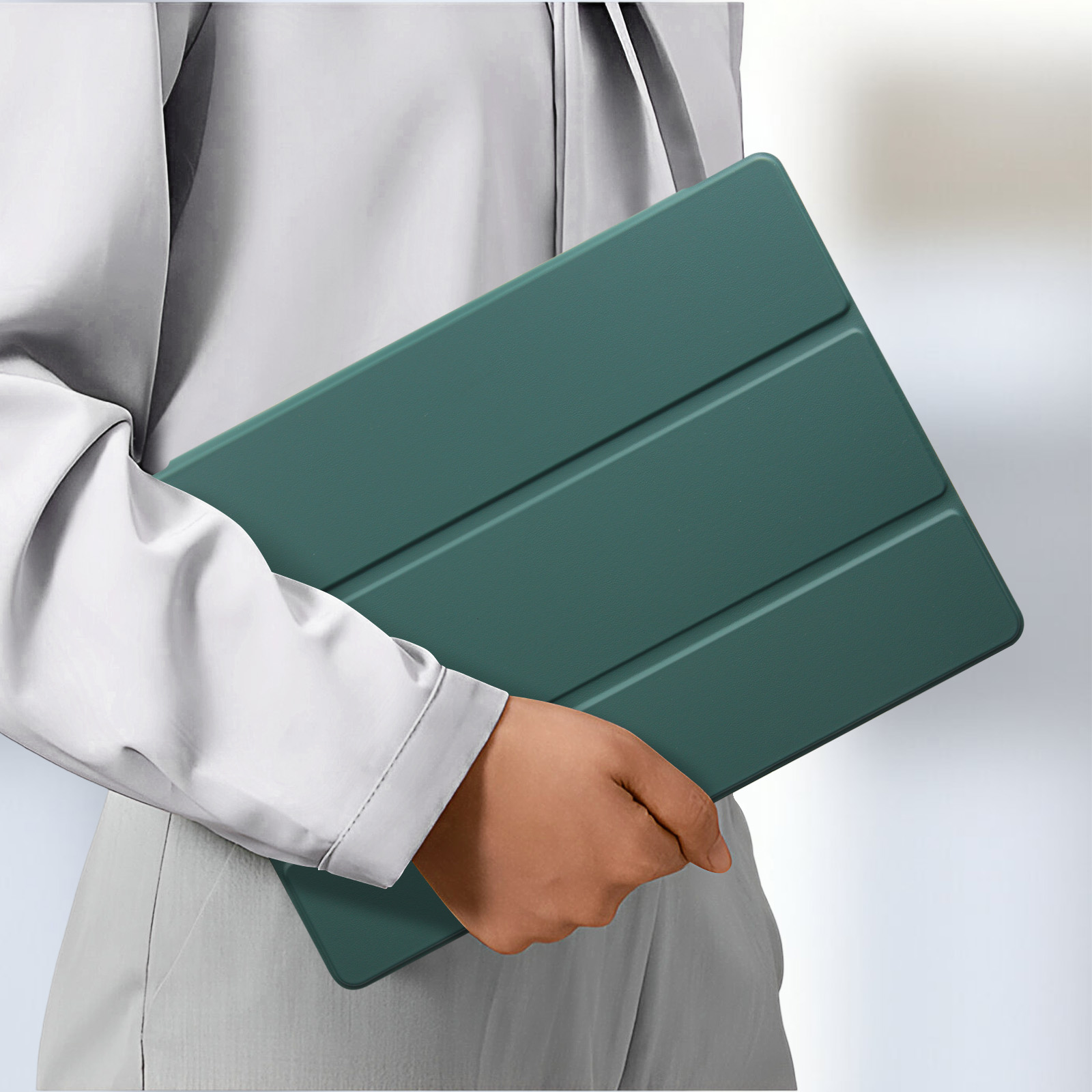 Una persona tiene in mano una custodia per tablet verde acqua chiusa. La custodia ha un design elegante e minimalista.