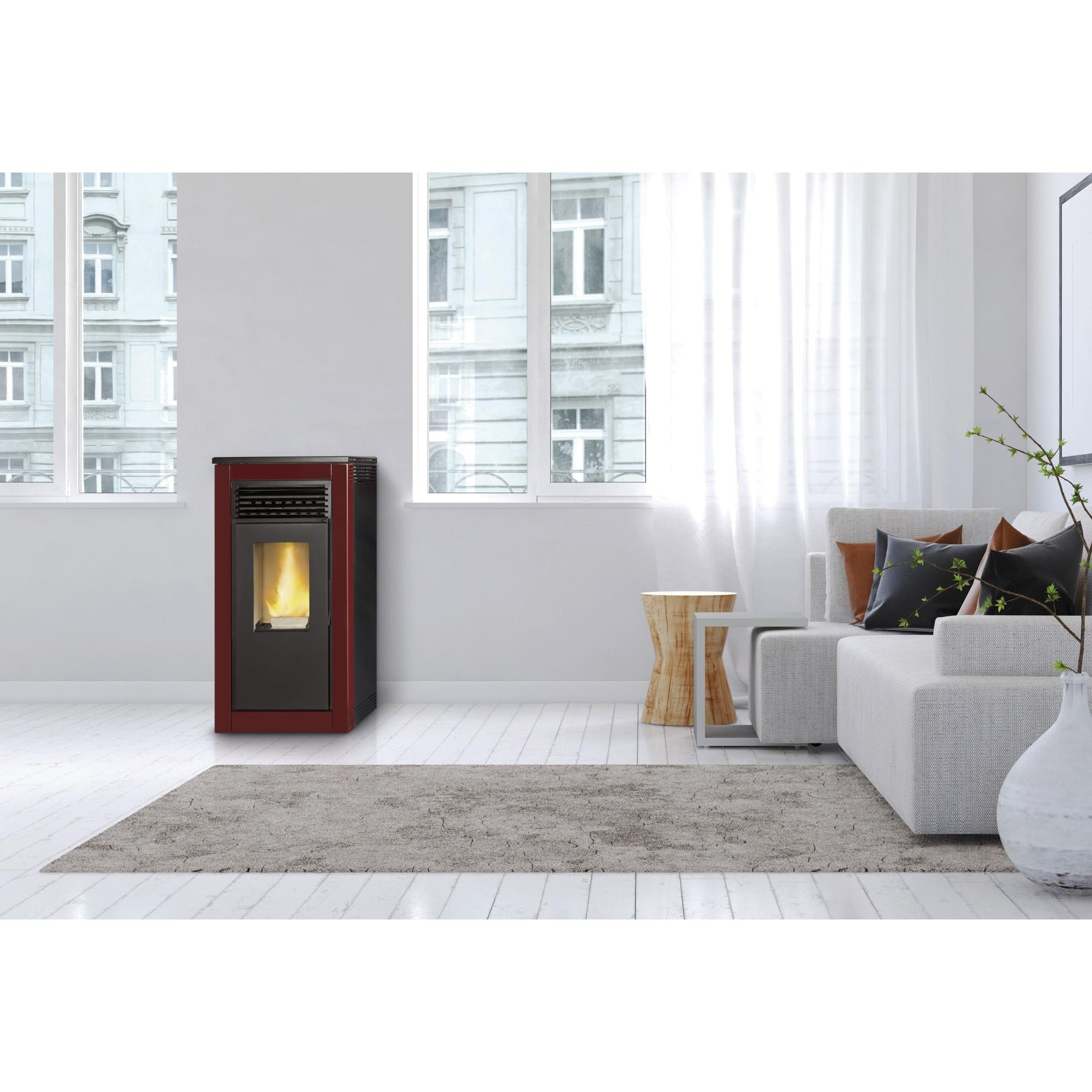 Chimenea roja y negra en una habitación blanca cerca de un sofá blanco y una ventana.