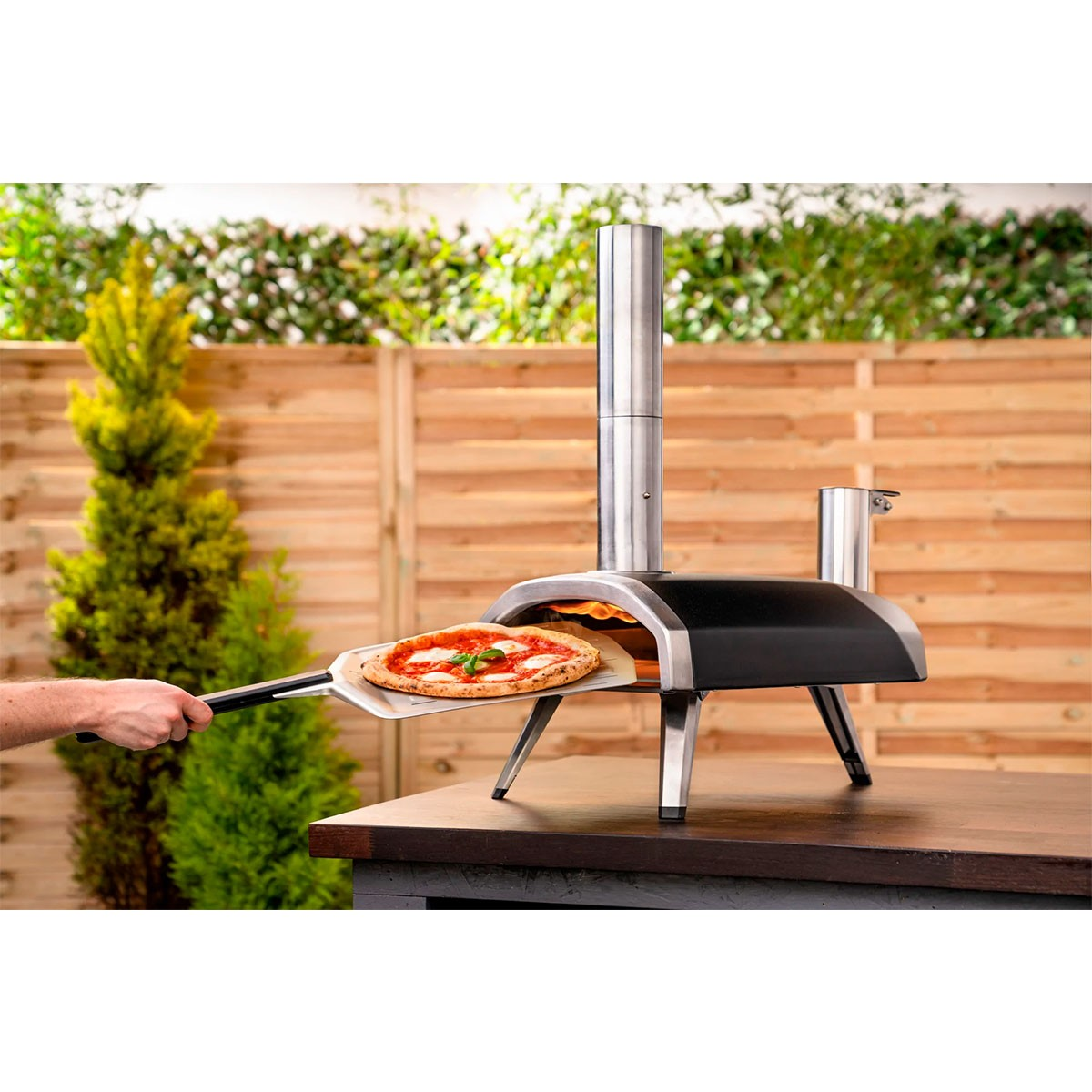 Una pizza viene rimossa da un forno per pizza all'aperto con una pala.