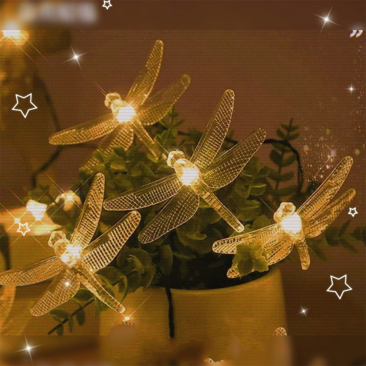 Libellenlichter in einer Vase. Warme, goldene Farbtöne. Sterne im Hintergrund sorgen für Festlichkeit.