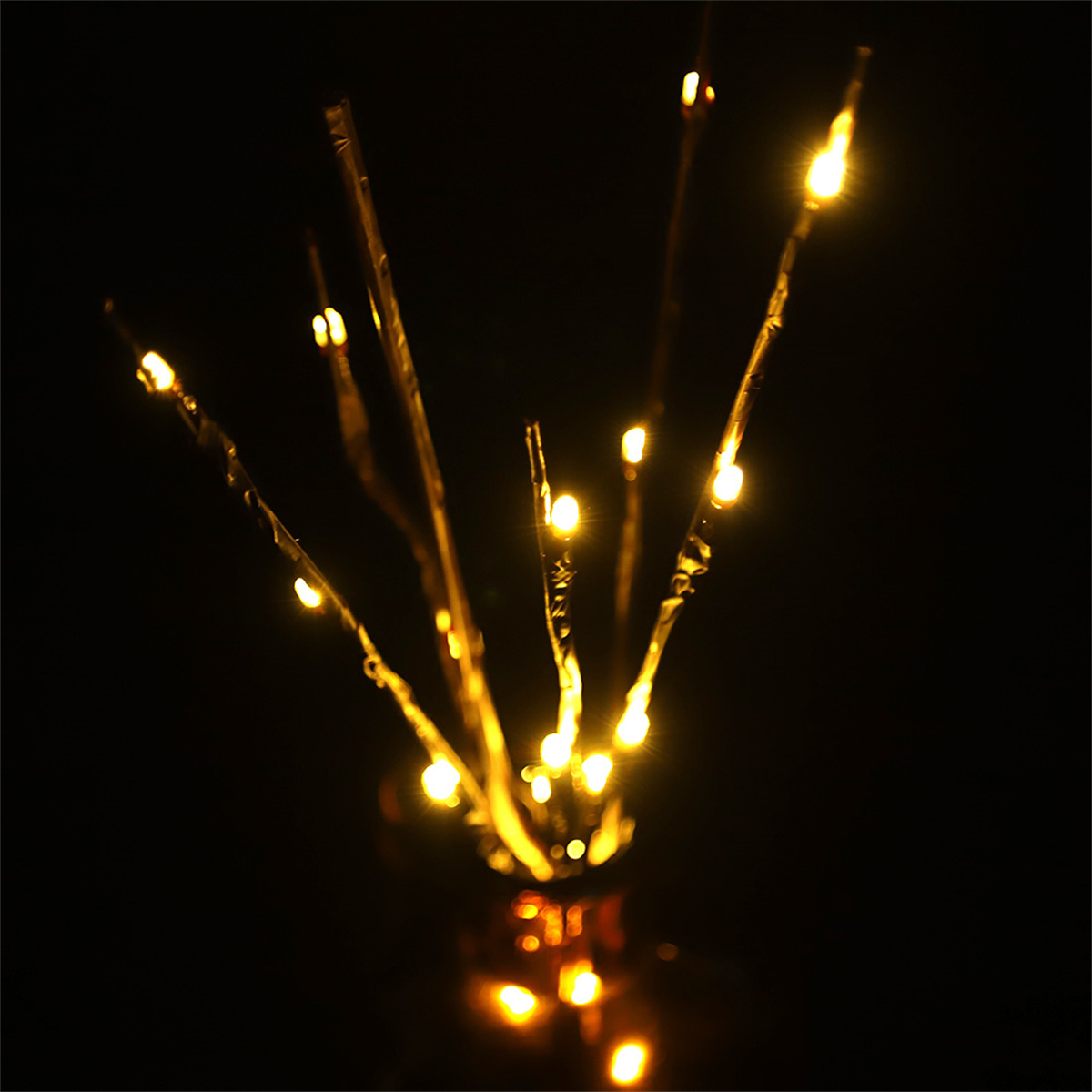 Nahaufnahme von beleuchteten Ästen mit gelben Lichtern vor schwarzem Hintergrund.