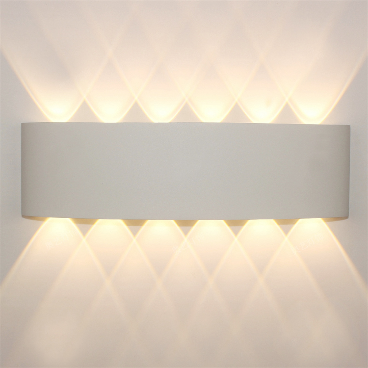 Eine weiße Wandleuchte mit mehreren nach unten scheinenden Lichtstrahlen.