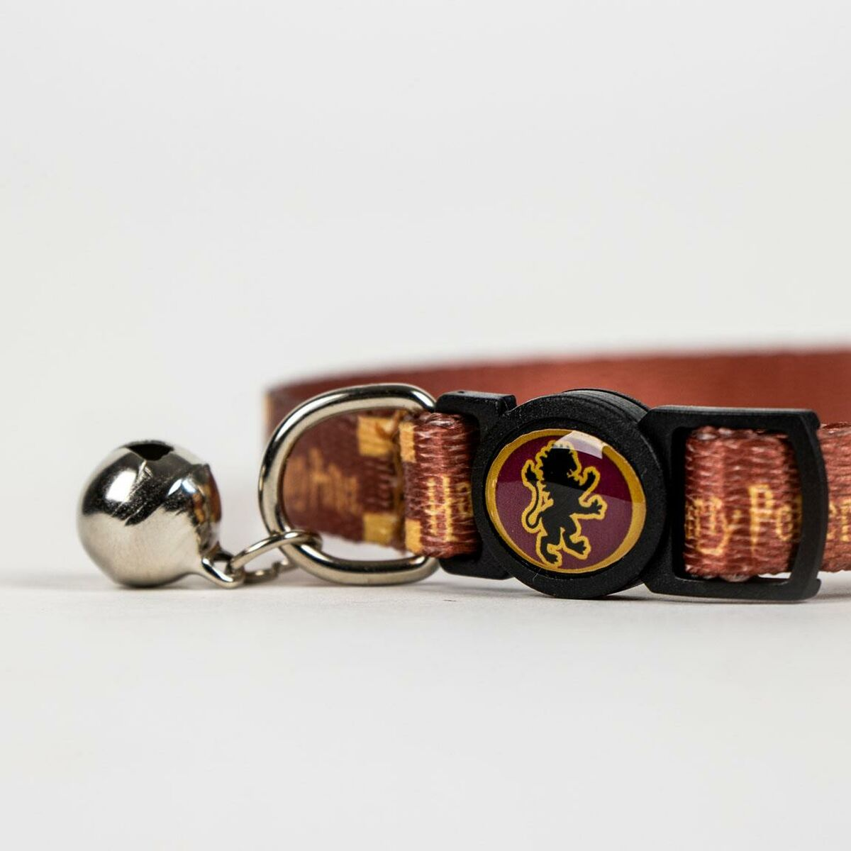 Braunes Katzenhalsband mit Glöckchen und Emblem. Weißer Hintergrund.
