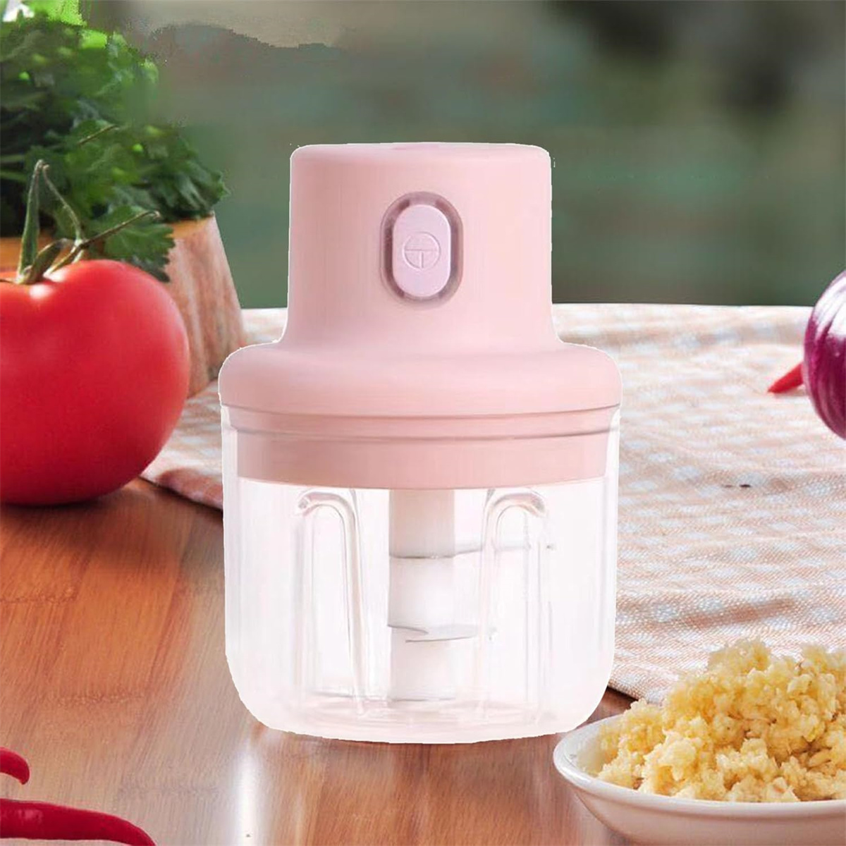 Rosa Mini-Küchenmaschine mit transparentem Behälter und gehacktem Knoblauch.