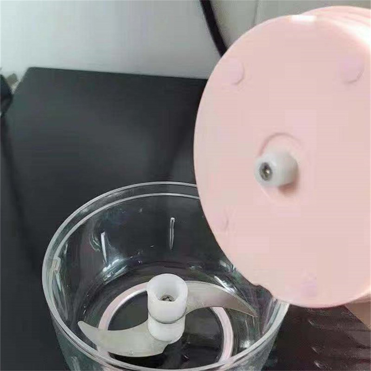 Ein pinkfarbener Mini-Zerkleinerer mit Klinge im Inneren wird gezeigt.