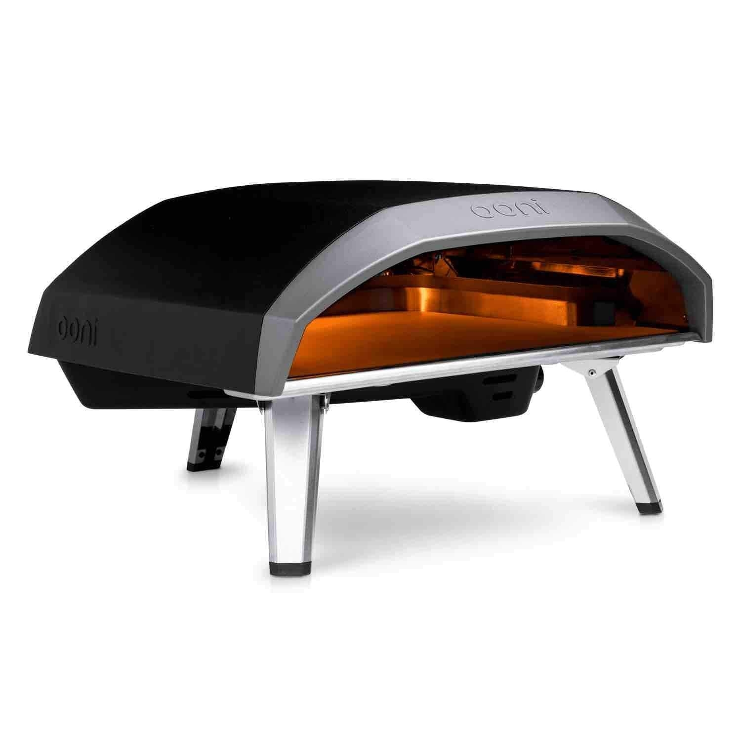 Forno per pizza Ooni nero su una superficie bianca. Gambe e dettagli argentati. Bagliore arancione all'interno.
