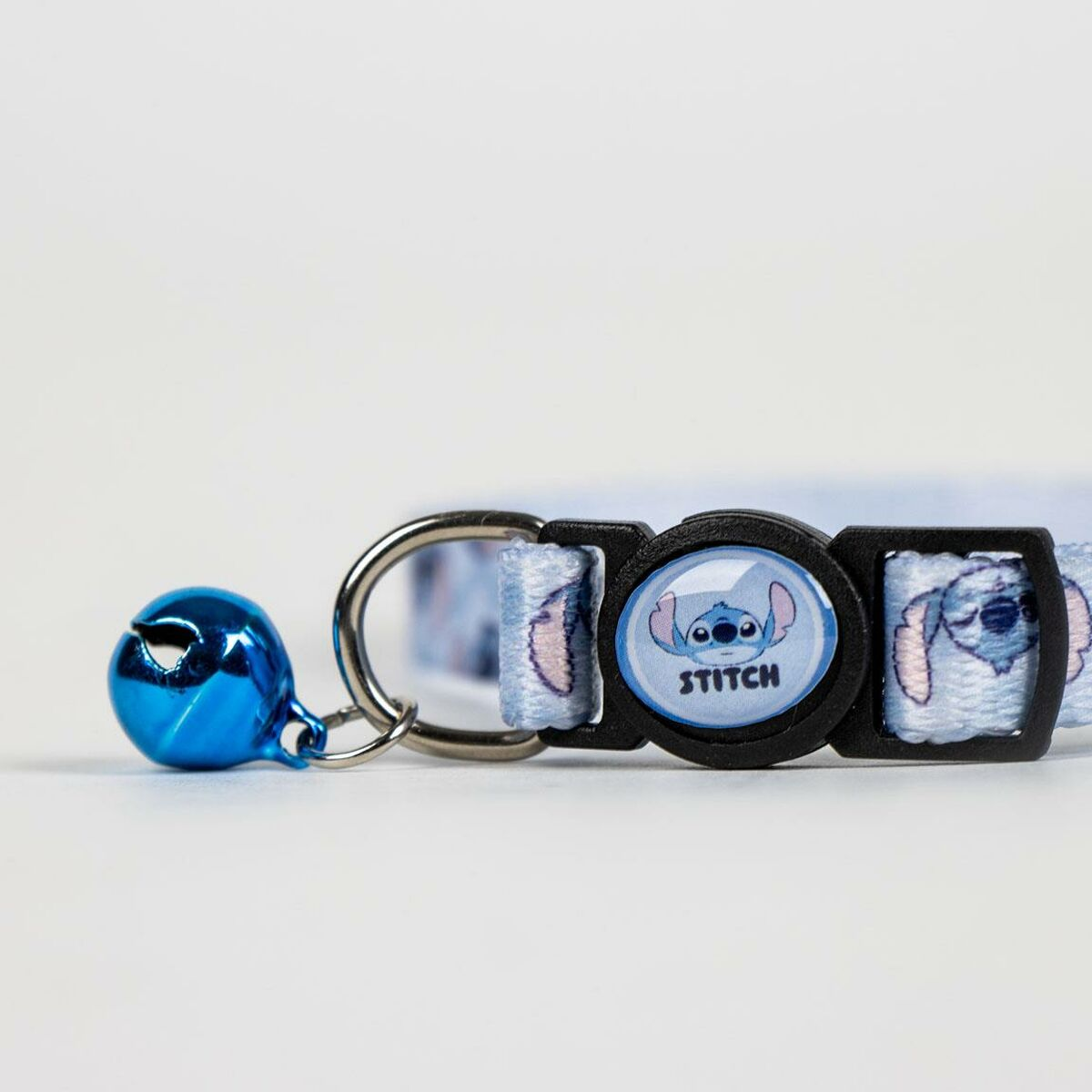 Ein hellblaues Katzenhalsband mit Stitch-Design und einer blauen Glocke, die an einem silbernen Ring befestigt ist.
