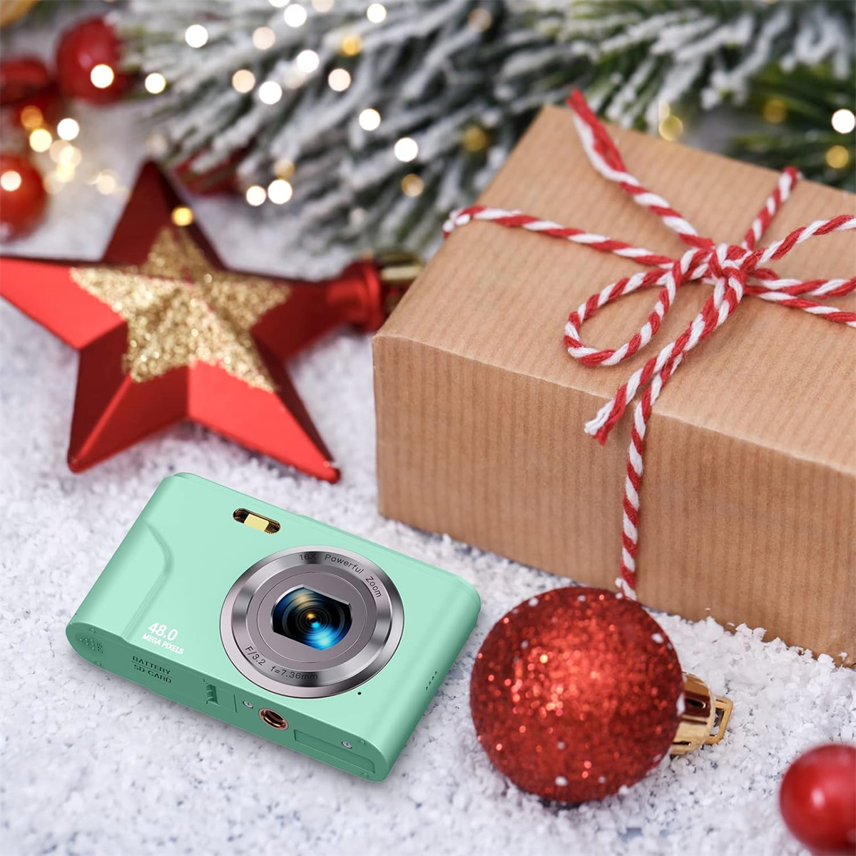 Eine mintgrüne Kamera und Geschenkbox mit rotem Stern und Ball auf weißer Oberfläche.