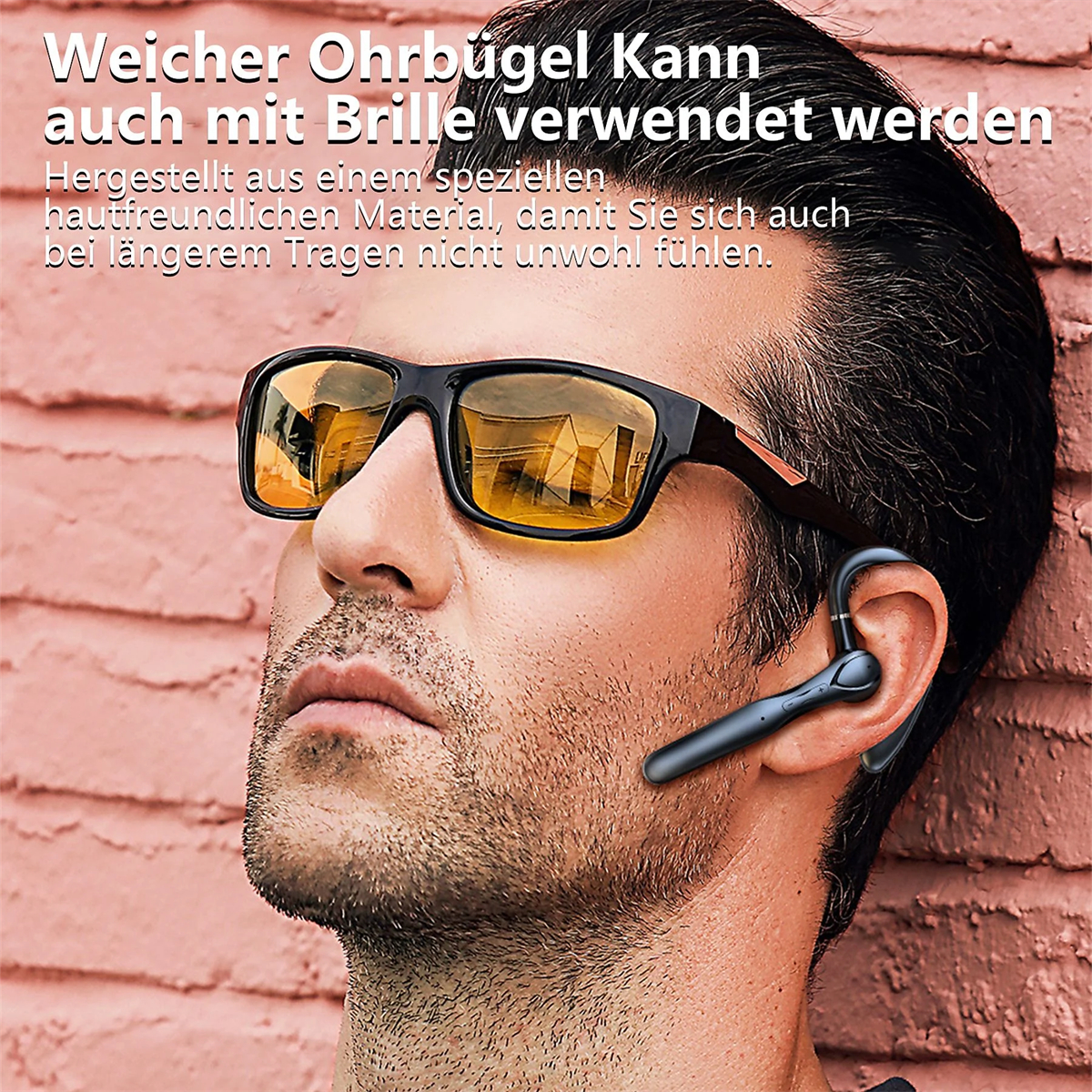 Mann mit schwarzer Sonnenbrille und blauem Kopfhörer, lehnt an einer roten Wand.