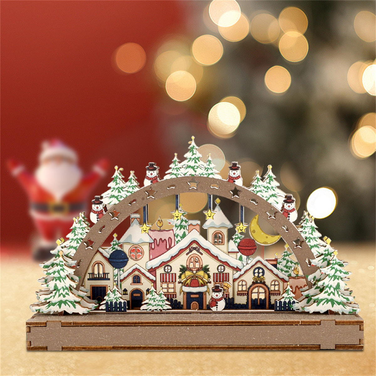 Eine hölzerne Weihnachtsdorf-Szene mit Häusern, Schneemännern und Bäumen. Der Weihnachtsmann ist im unscharfen Hintergrund.