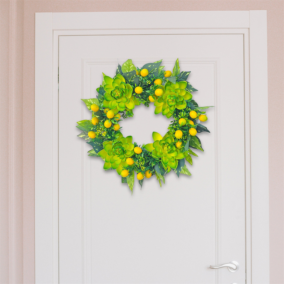Ein grüner und gelber Kranz an einer weißen Tür, mit natürlichem, blumigem Design.