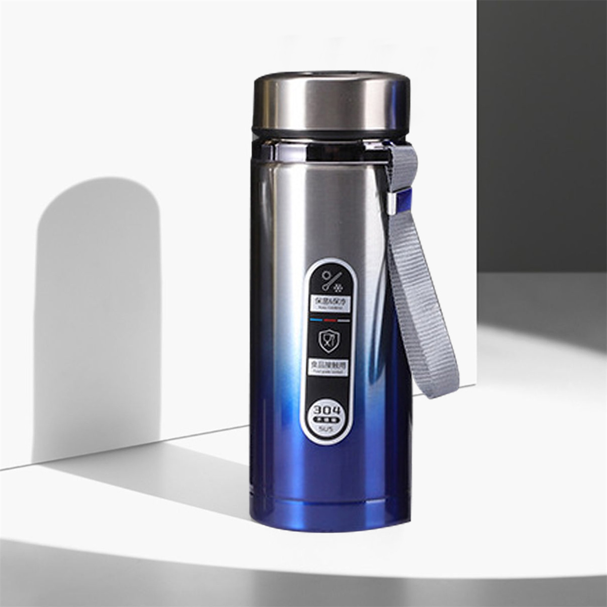 Eine blau-silberne Wasserflasche mit Riemen, platziert auf weißer Oberfläche.