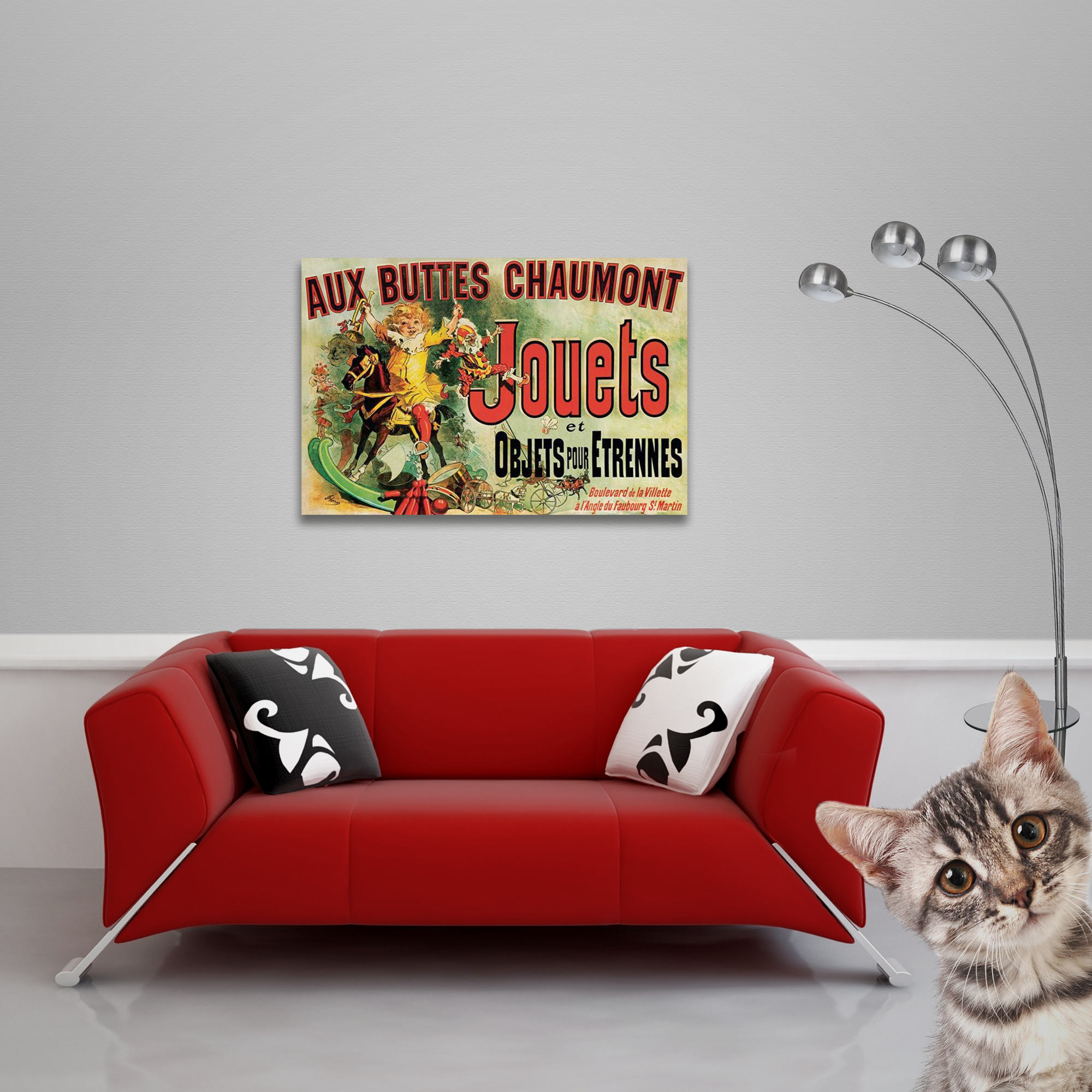 Ein Vintage-Poster an einer Wand über einem roten Sofa, mit einer Katze in der Ecke.