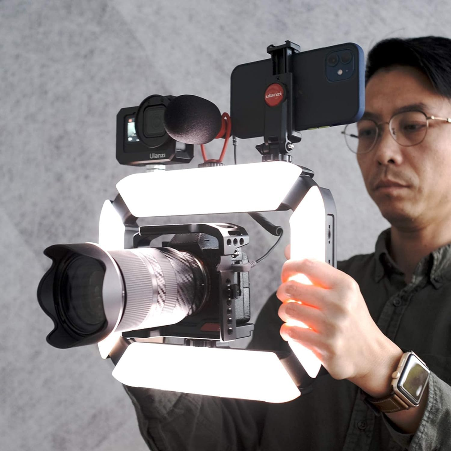 Uomo che tiene un rig per fotocamera con luci, microfono e supporto per telefono.