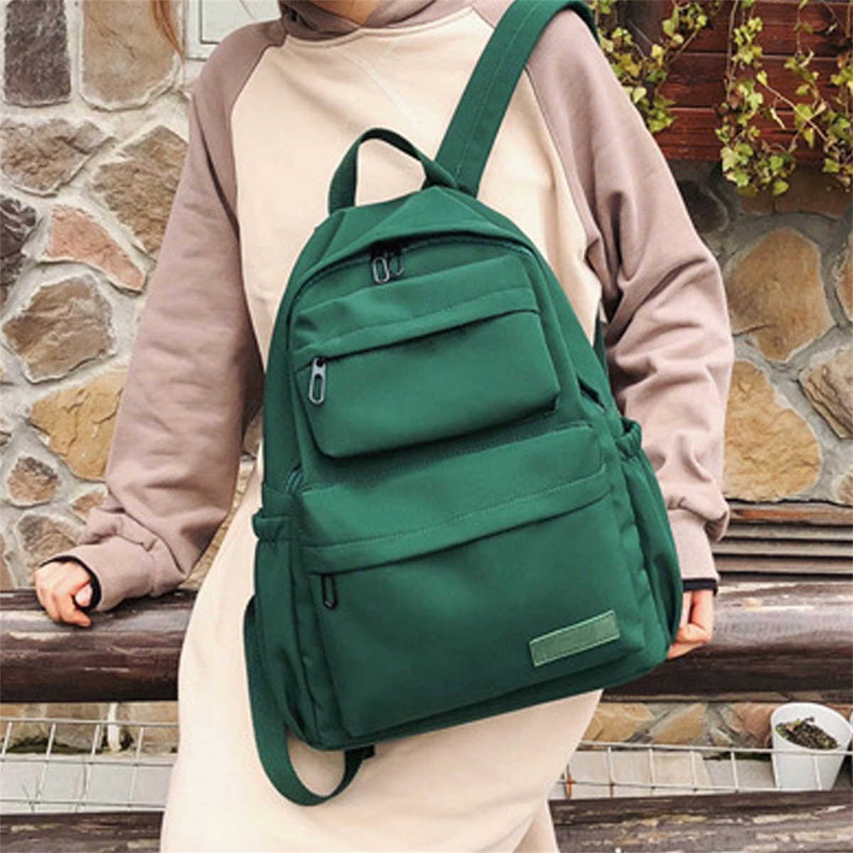 Frau mit beigem Pullover und grünem Rucksack. Der Rucksack hat mehrere Taschen.