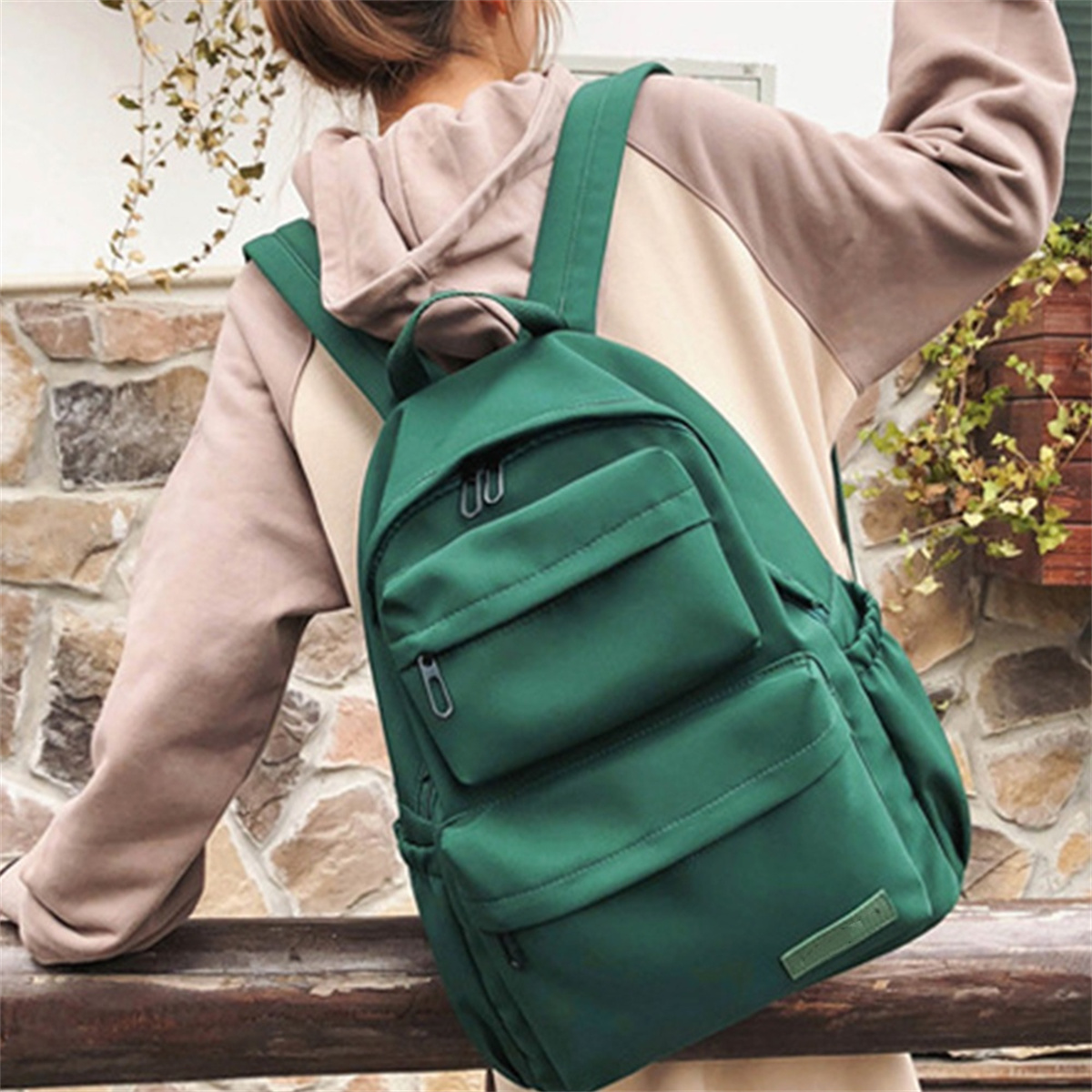Eine Frau mit einem grünen Rucksack. Der Rucksack hat Taschen und Träger.