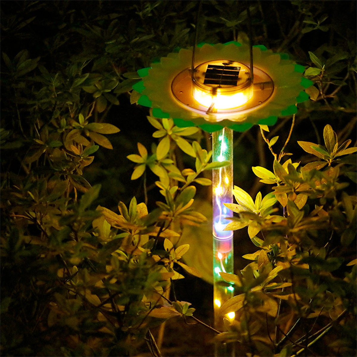 Solar-Gartenleuchte mit grünen Blättern und einem leuchtenden Licht bei Nacht.