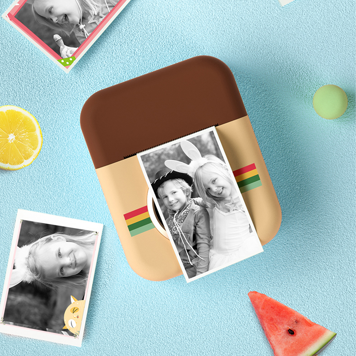 Ein Fotodrucker mit Fotos, einer Scheibe Wassermelone und einem grünen Ball auf blauer Oberfläche.