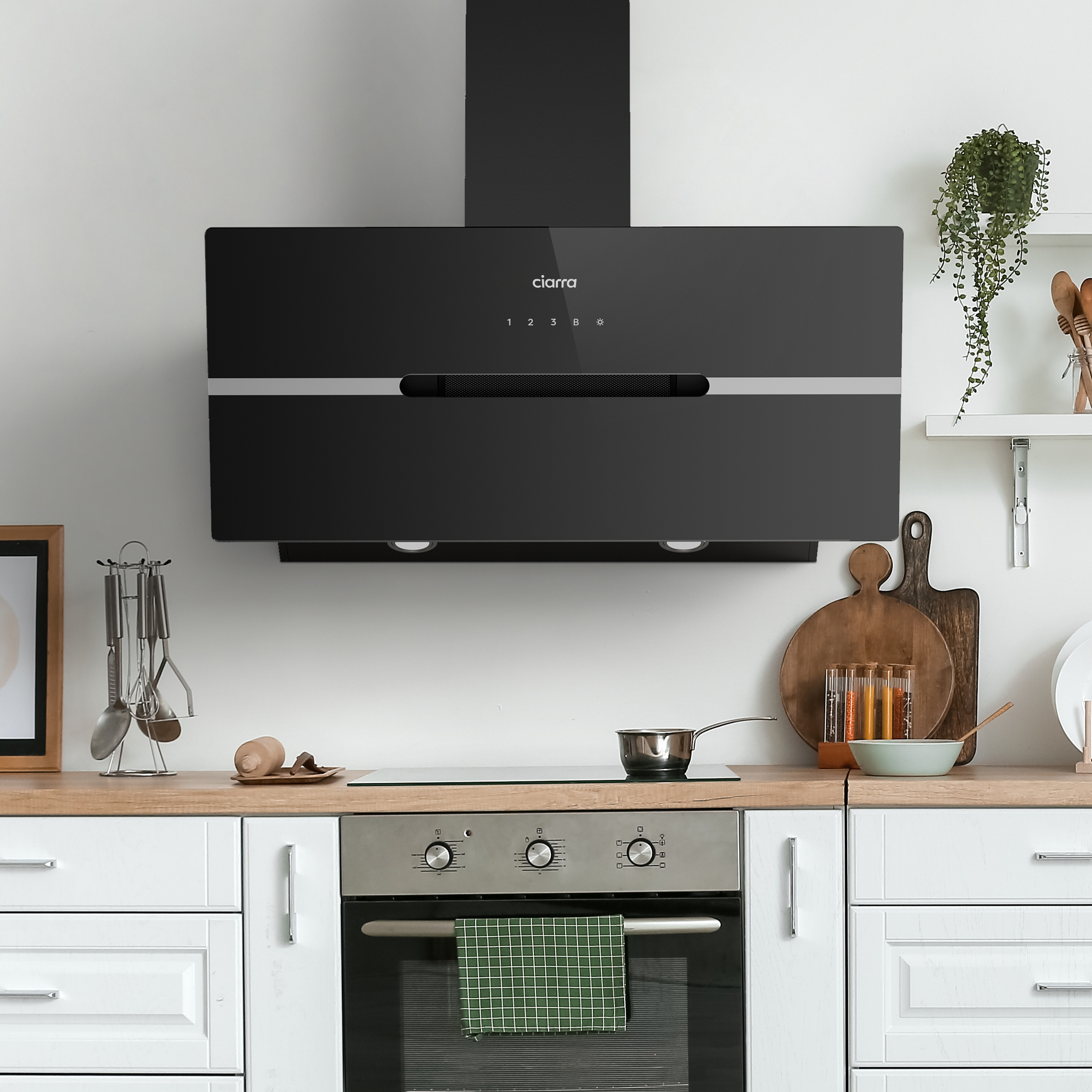 Keuken met zwarte afzuigkap, oven en houten aanrecht. Pan op het fornuis.