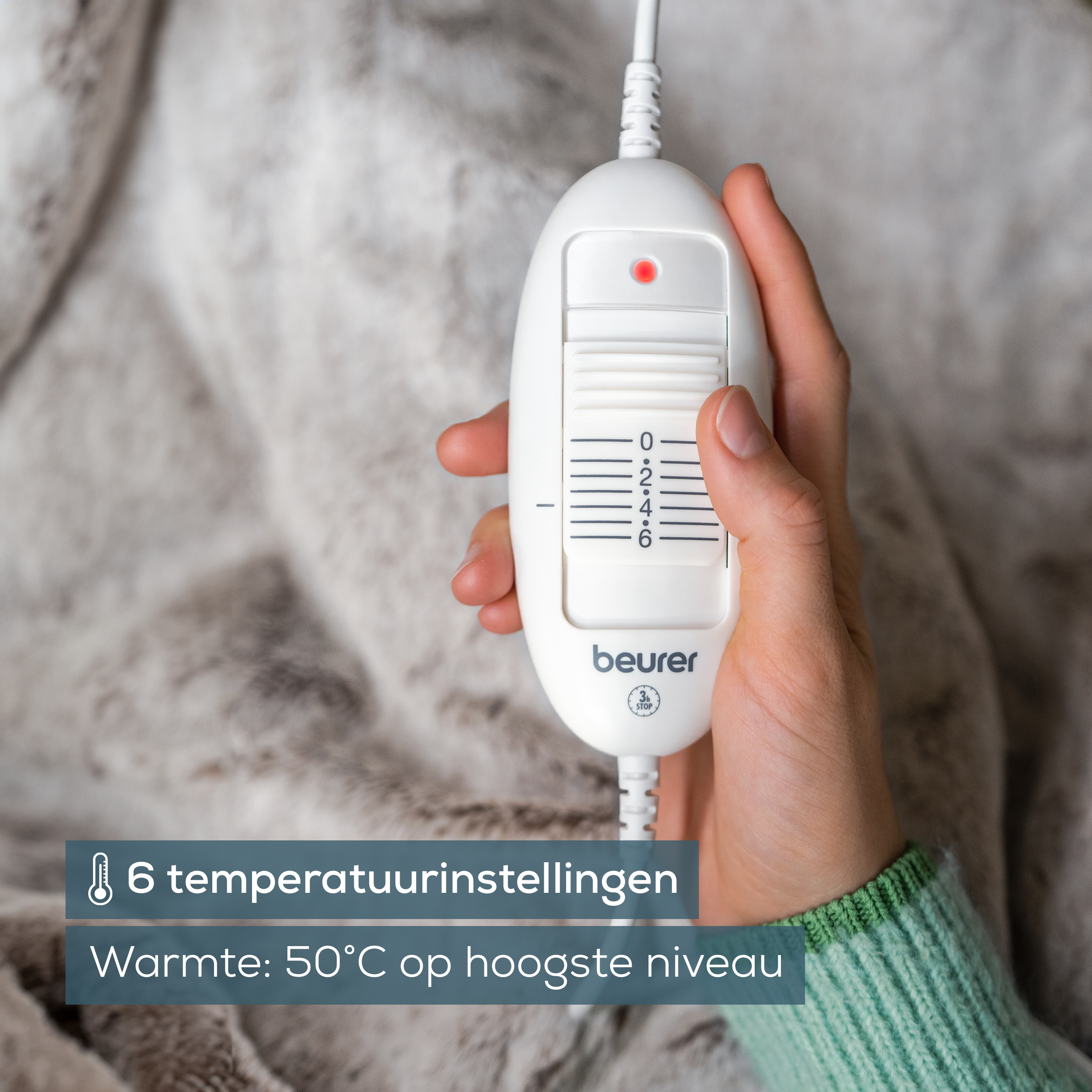 Mano sosteniendo el controlador blanco de la manta eléctrica con ajustes de temperatura.