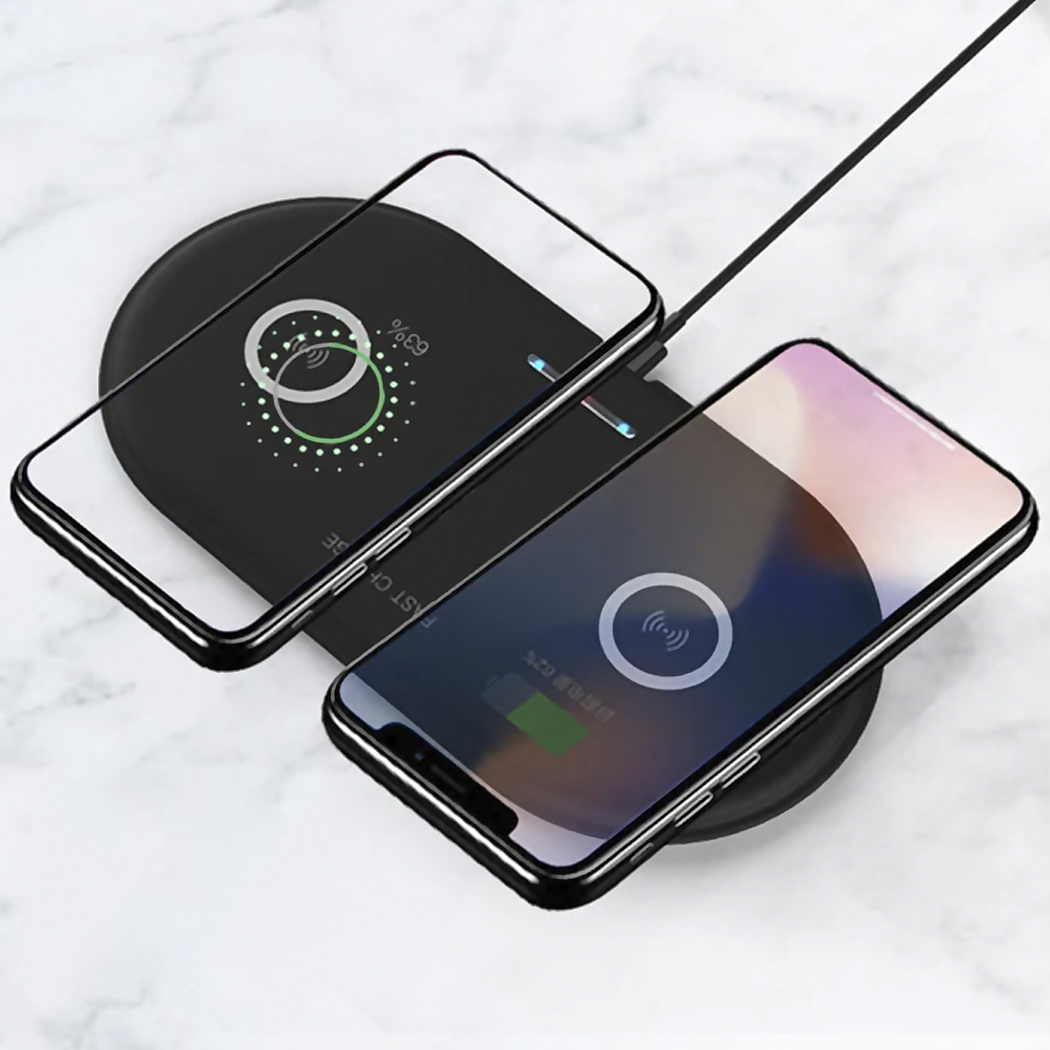 Due telefoni in carica wireless su un pad nero, con sfondo in marmo.