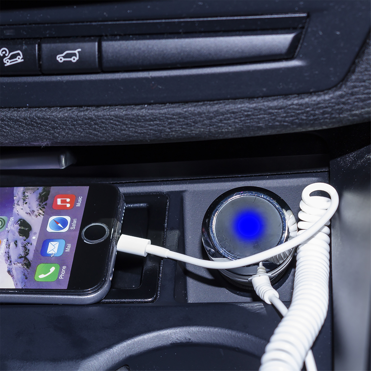 Un telefono che si carica in auto. Il caricatore si illumina di blu ed è visibile un cavo bianco.