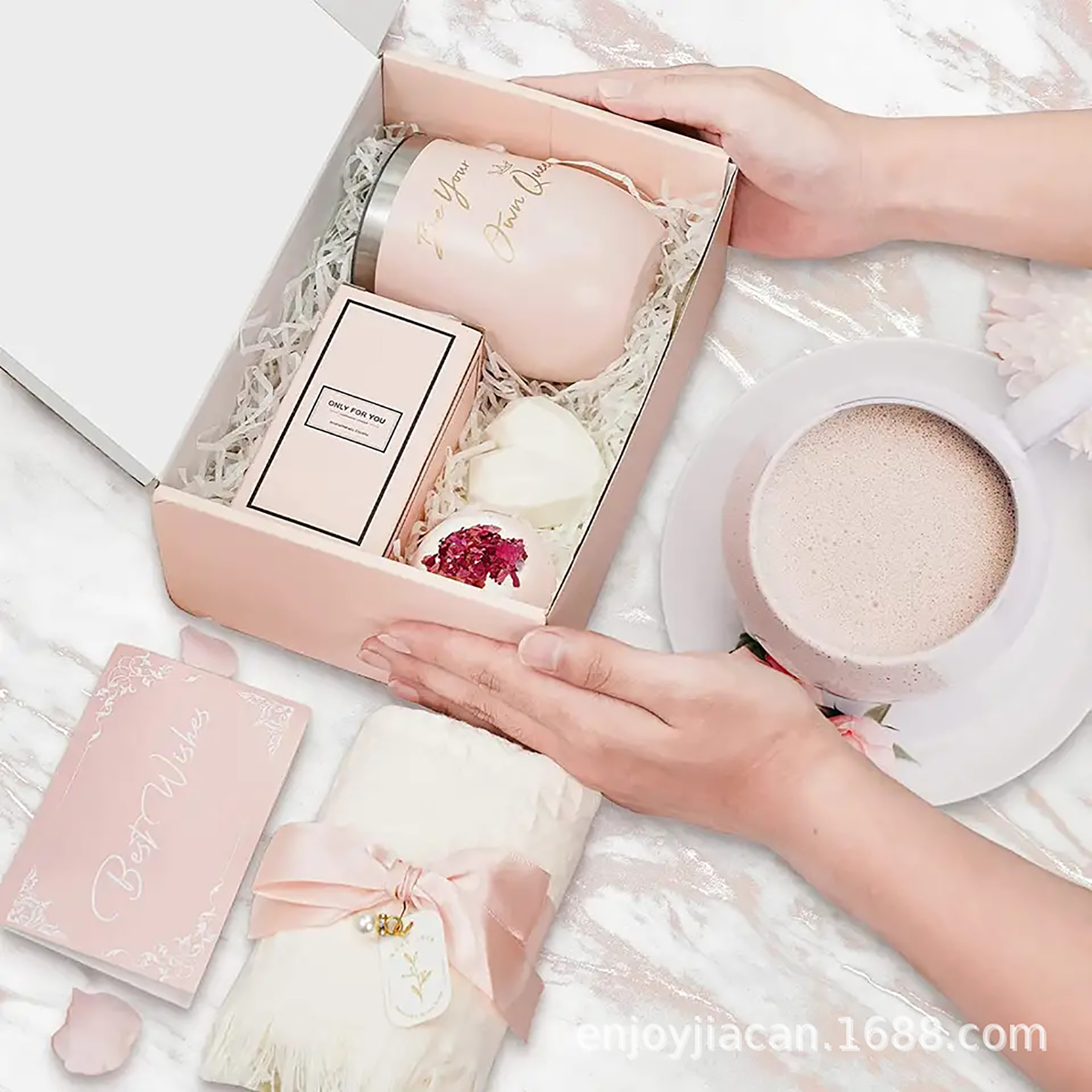 Eine Geschenkbox mit einer Tasse, einer Kerze, einem Handtuch, einer Karte und Händen, die eine Tasse halten.