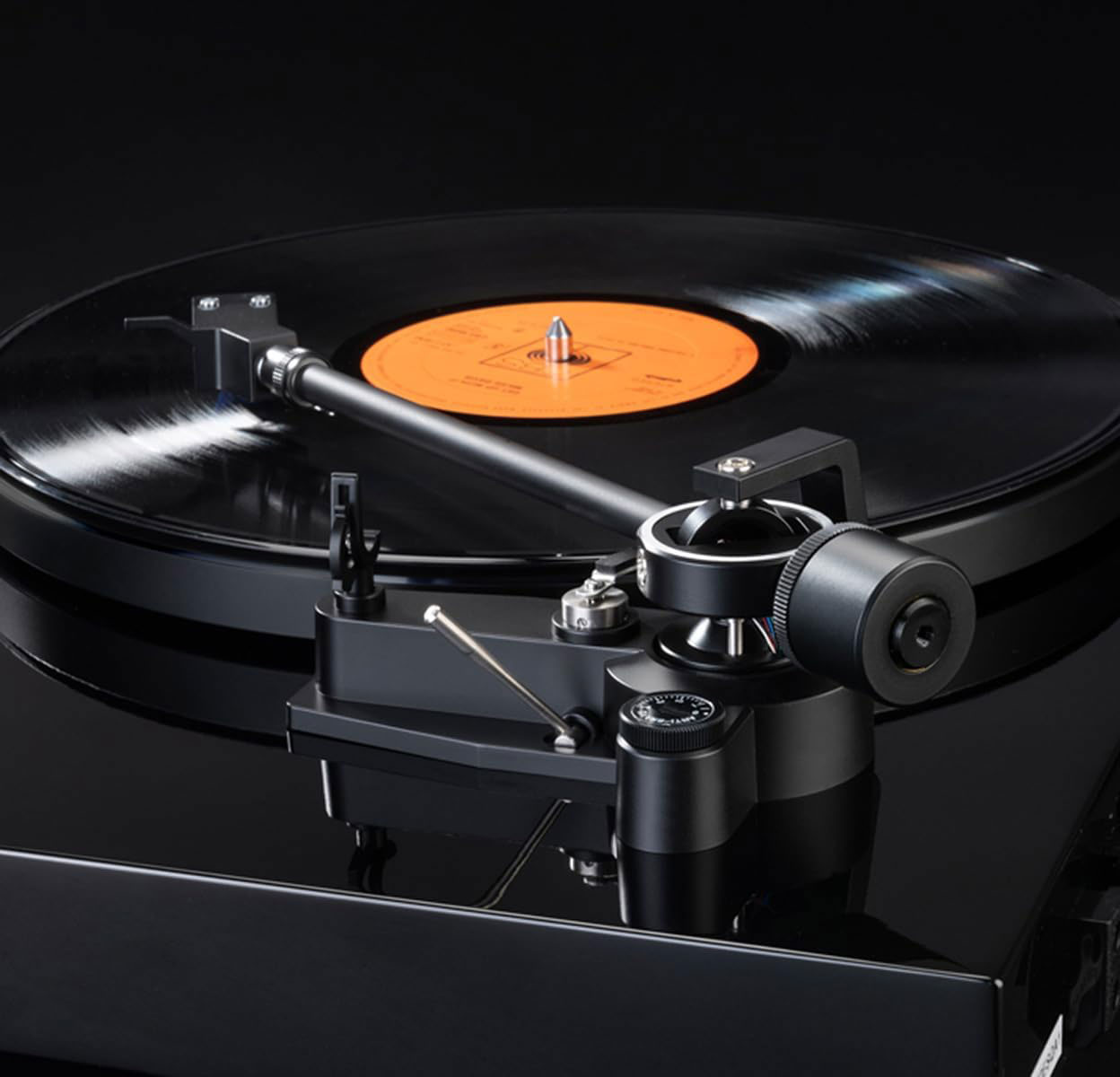 Nahaufnahme eines schwarzen Plattenspielers, der eine Vinylplatte abspielt, mit schwarzem Hintergrund.