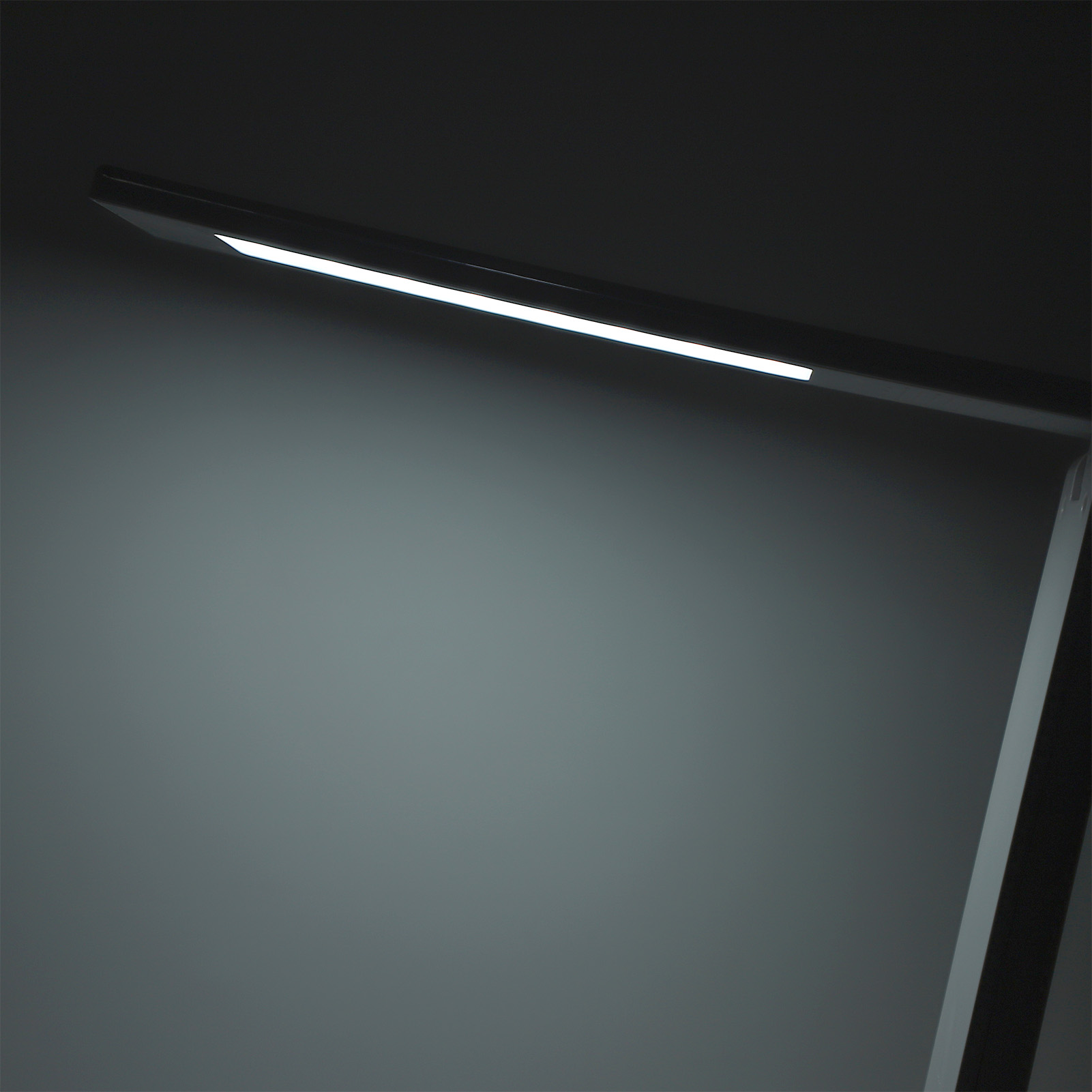 Moderne Schreibtischlampe mit hellem weißen LED-Licht. Dunkler Hintergrund.