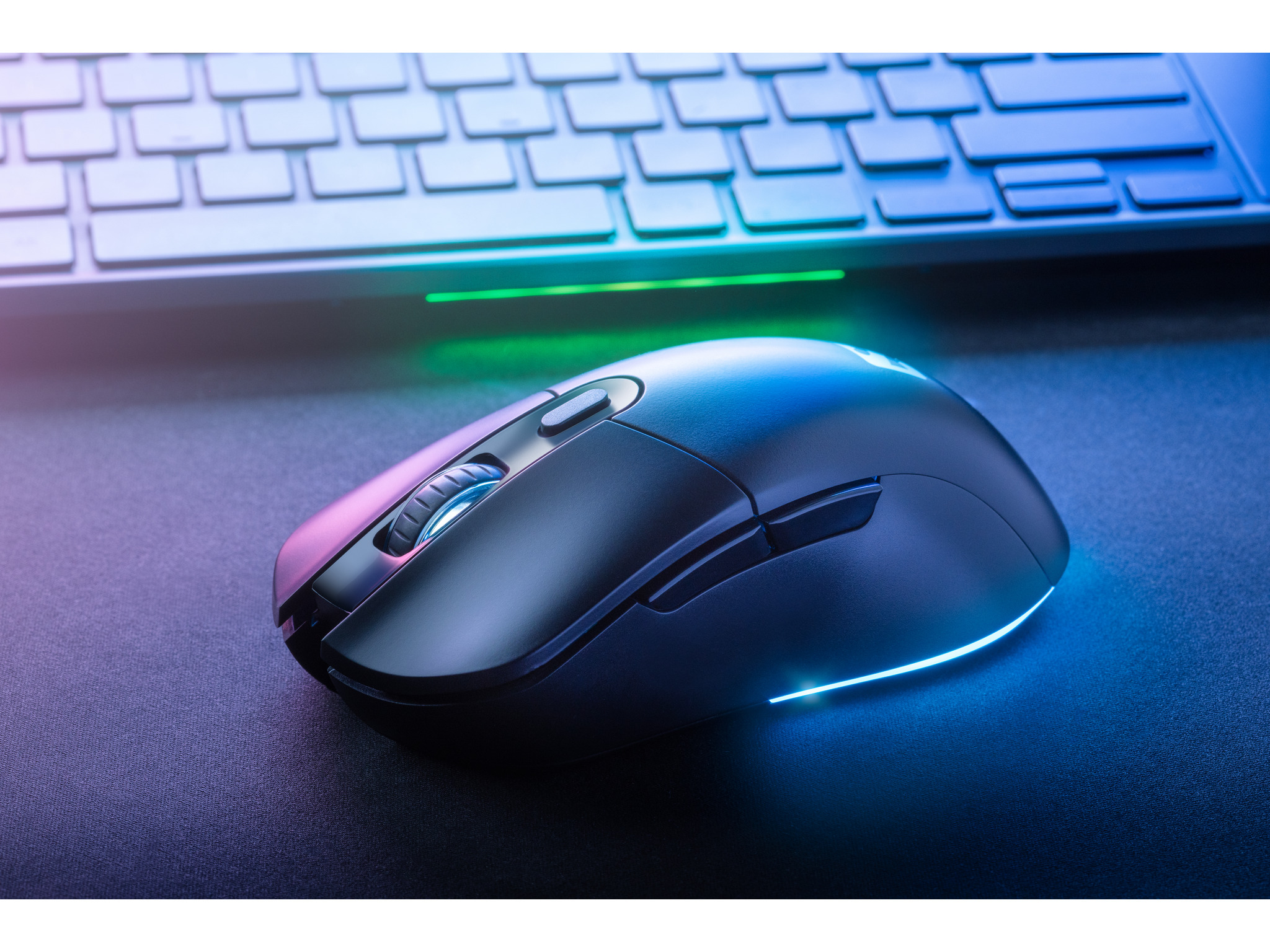 Czarna mysz na czarnej powierzchni z klawiaturą w tle.