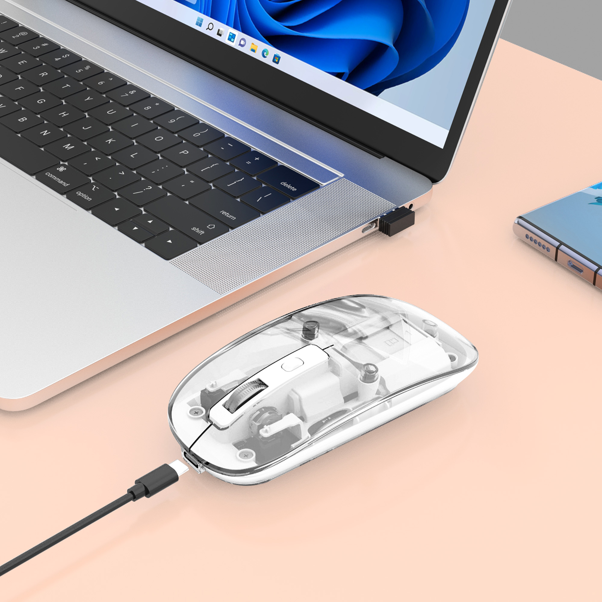 Un mouse trasparente con un cavo collegato a un laptop e un telefono.