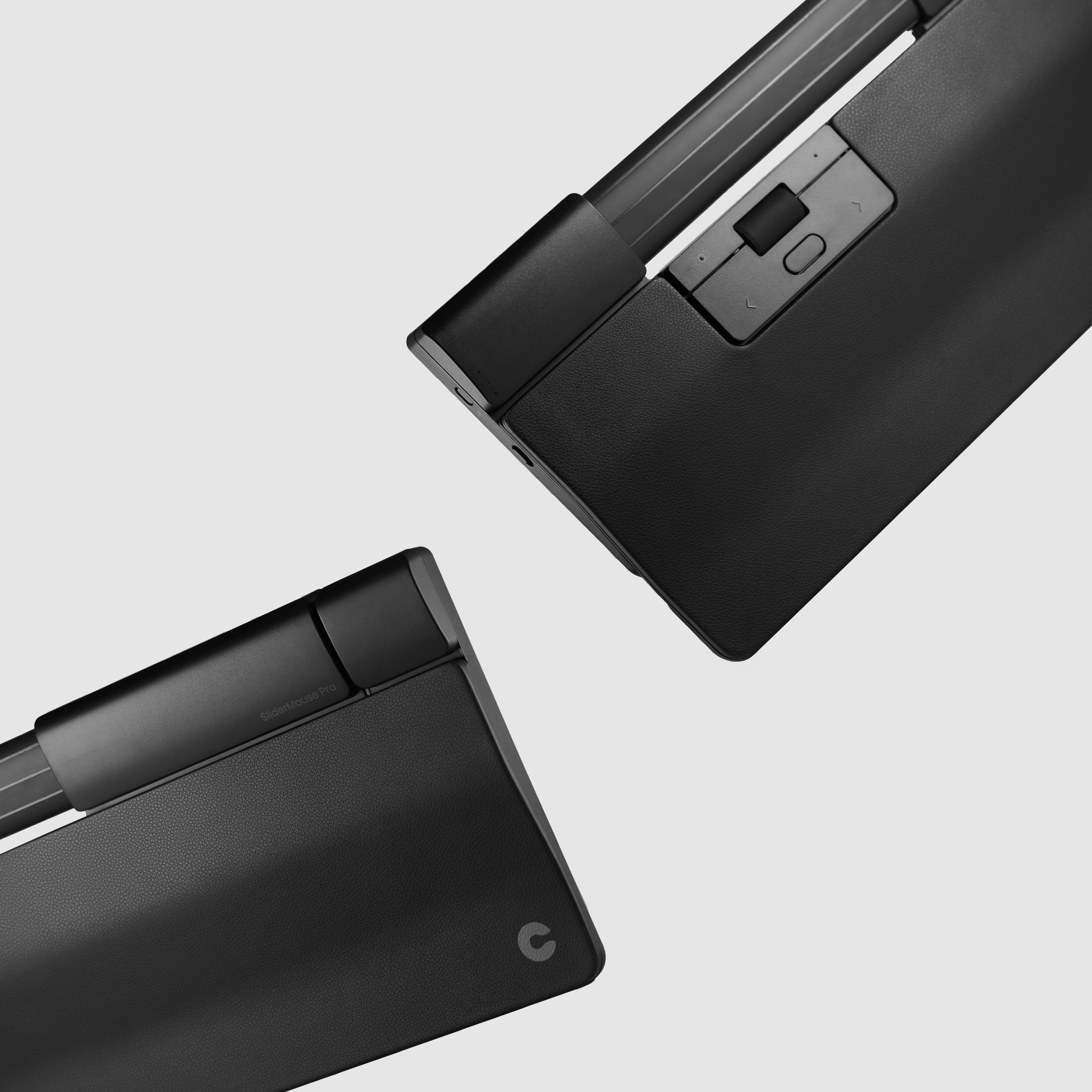 Dwa elementy SliderMouse Pro z czarnymi powierzchniami. Białe tło. Widoczne logo.