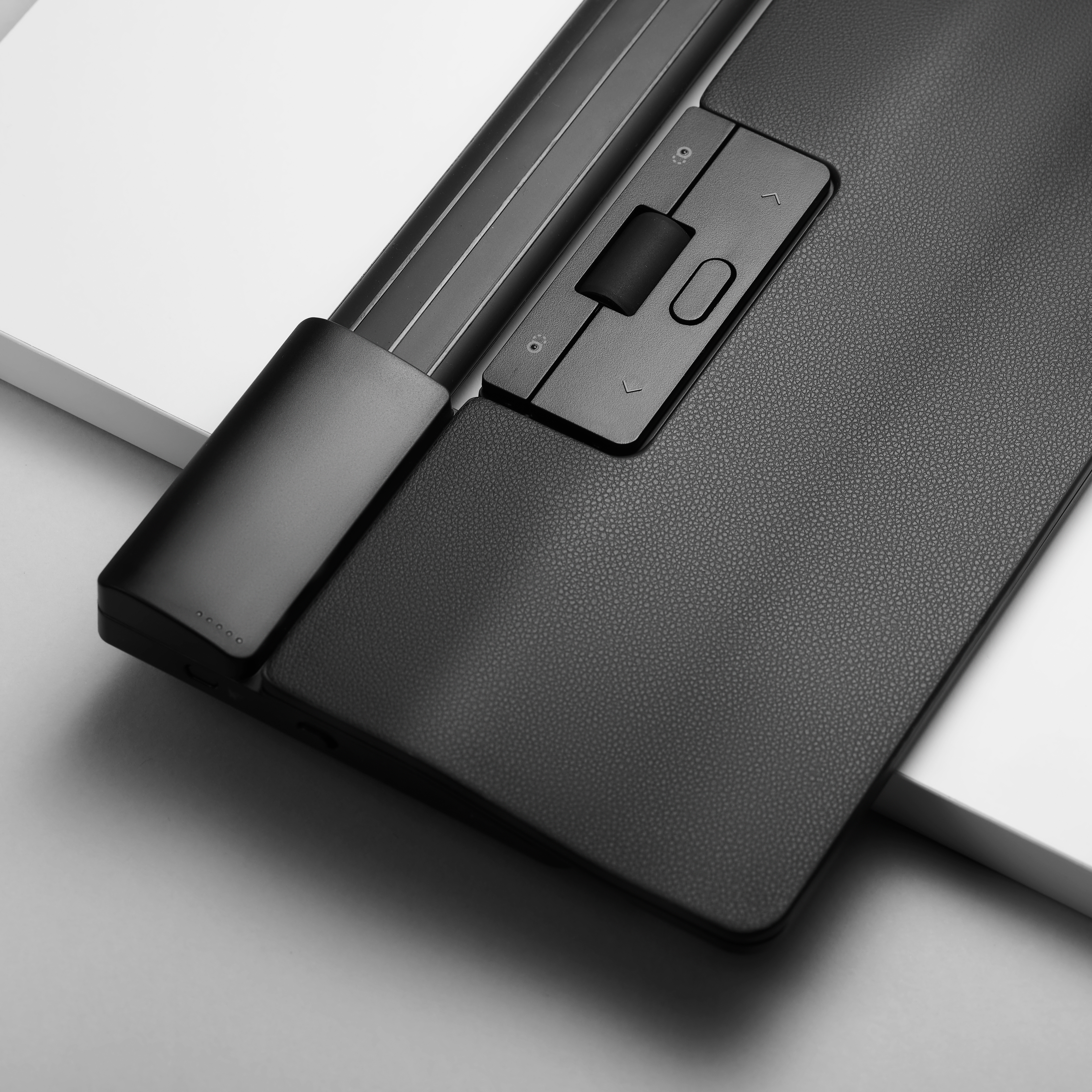 Teclado ergonómico negro con reposamuñecas y trackpad. Vista en ángulo, fondo blanco y gris.