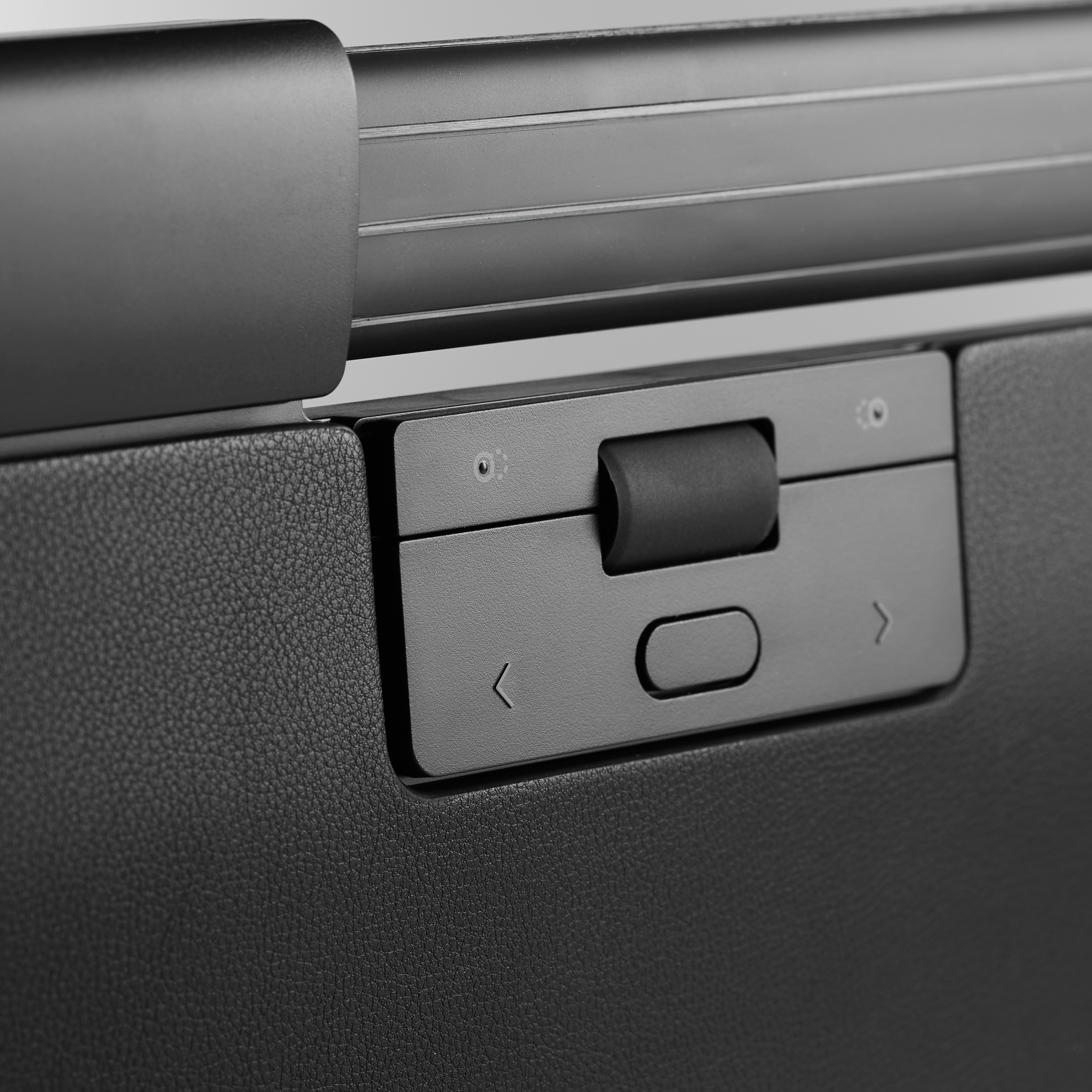 Primer plano del panel de control de un teclado ergonómico negro con flechas y una perilla. Textura de cuero negro.