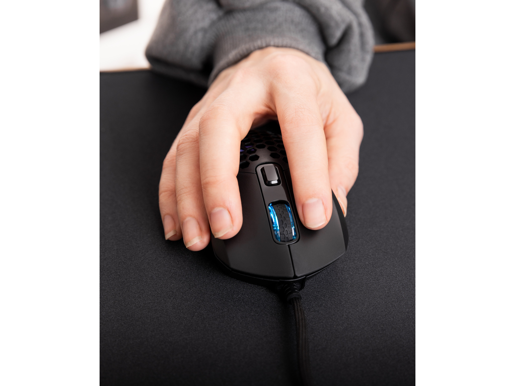 Een hand die een zwarte gamingmuis op een zwarte muismat vasthoudt.