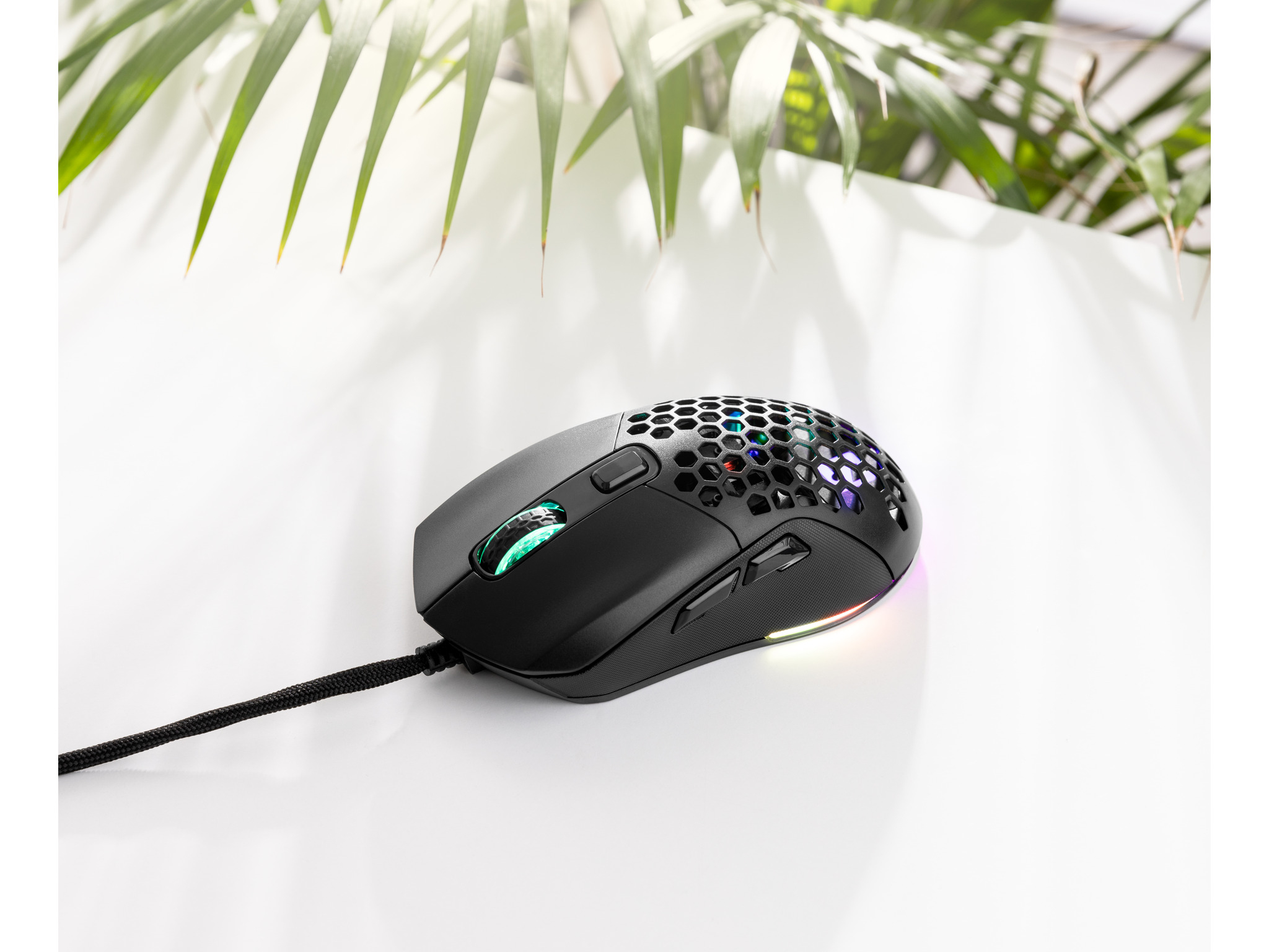 Zwarte gamingmuis met honingraatontwerp, RGB-verlichting, op wit oppervlak.
