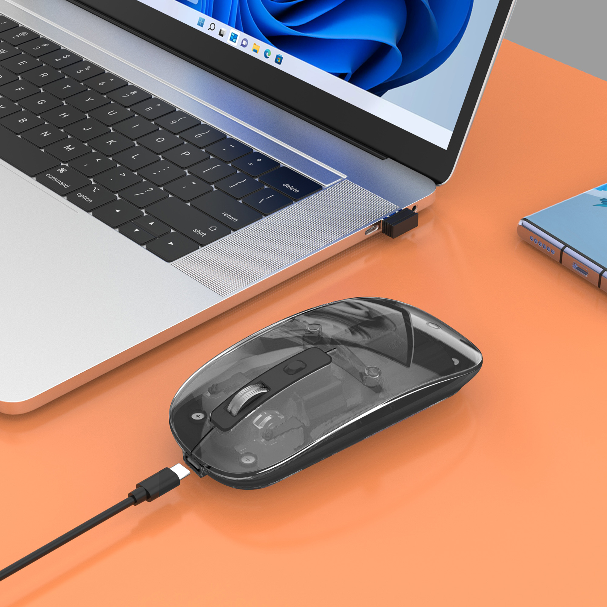 Mouse wireless nero collegato a un laptop. Il mouse è su una superficie arancione.