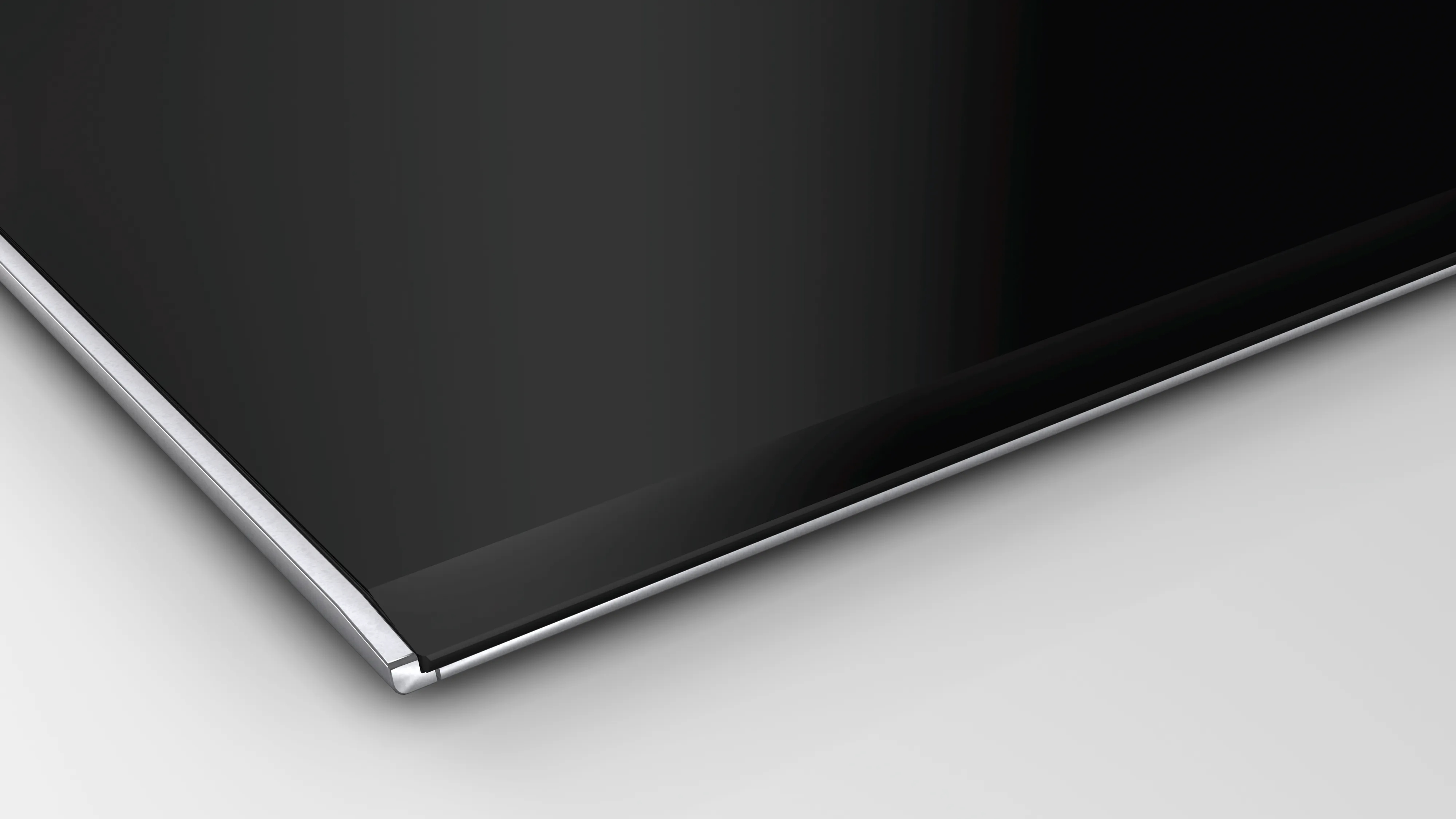 Una superficie rectangular negra y brillante con un borde metálico, probablemente parte de un electrodoméstico moderno.