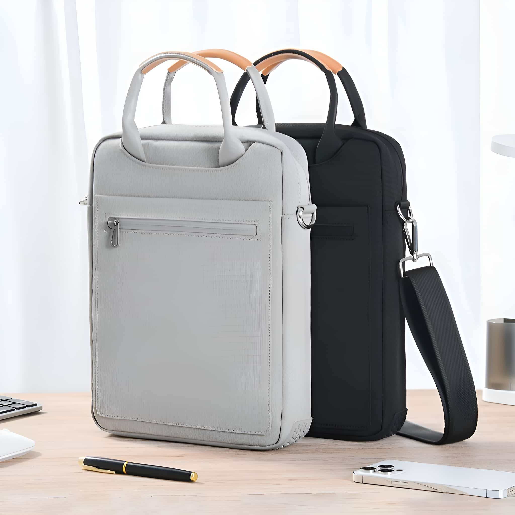 Zwei Laptoptaschen, eine graue und eine schwarze, auf einem Holztisch.